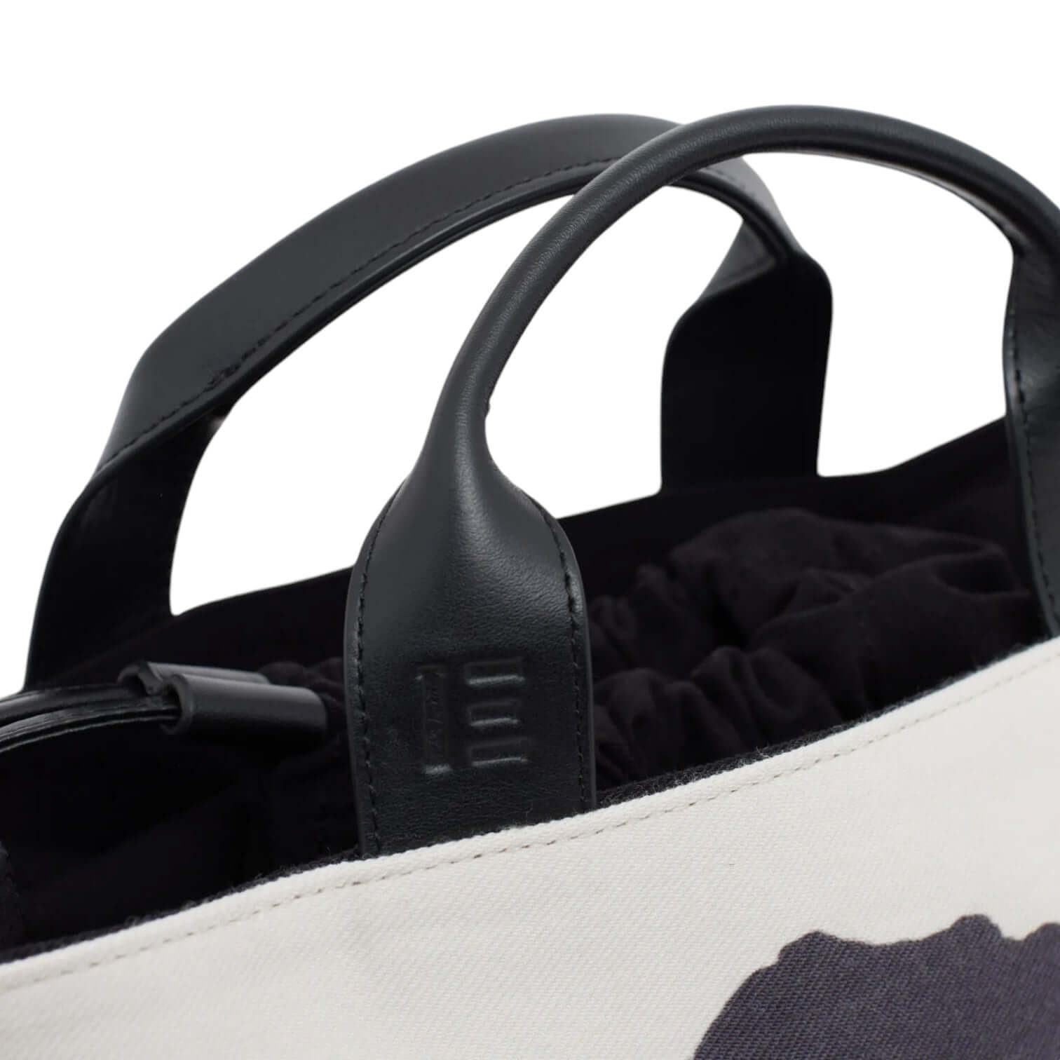 Close-up of the Nomade Montagne handbag featuring black leather handles and a drawstring closure.
