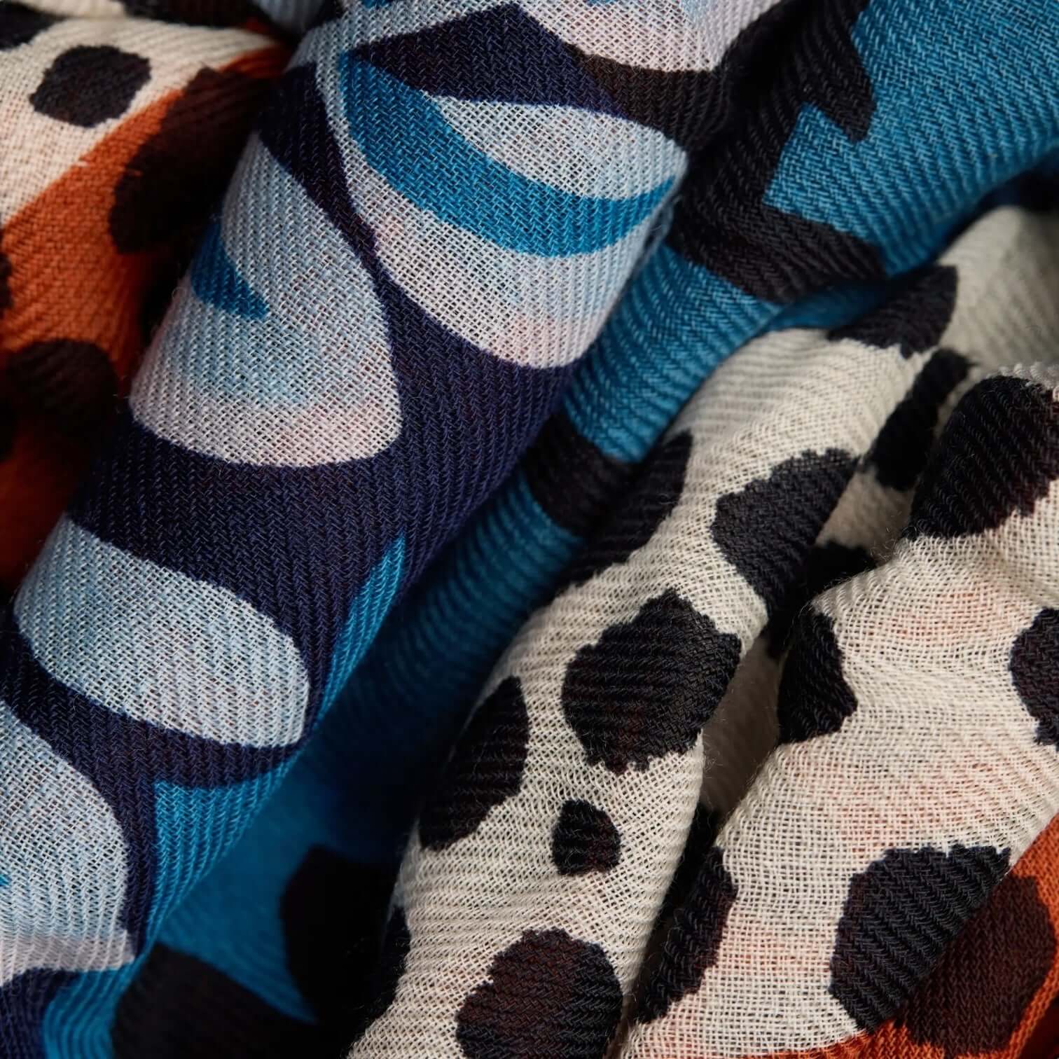 Colorful patterned fabric of Sciarpa Mike Blu, featuring unique designs in blue, orange, and black, ideal for stylish outfits.