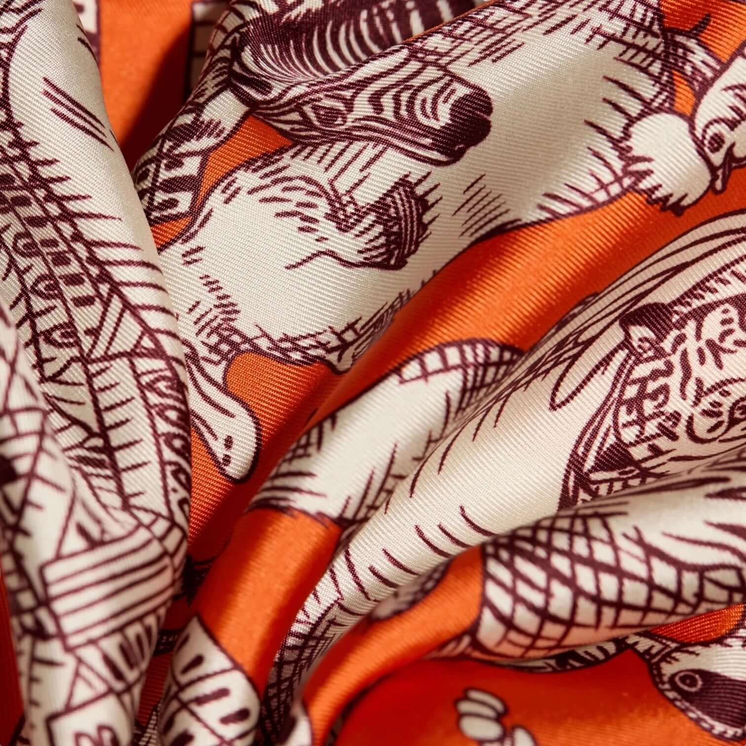 Foulard Quadrato Turgot Orange, 70x70 cm, versatile accessory featuring intricate animal patterns in vibrant orange and cream.