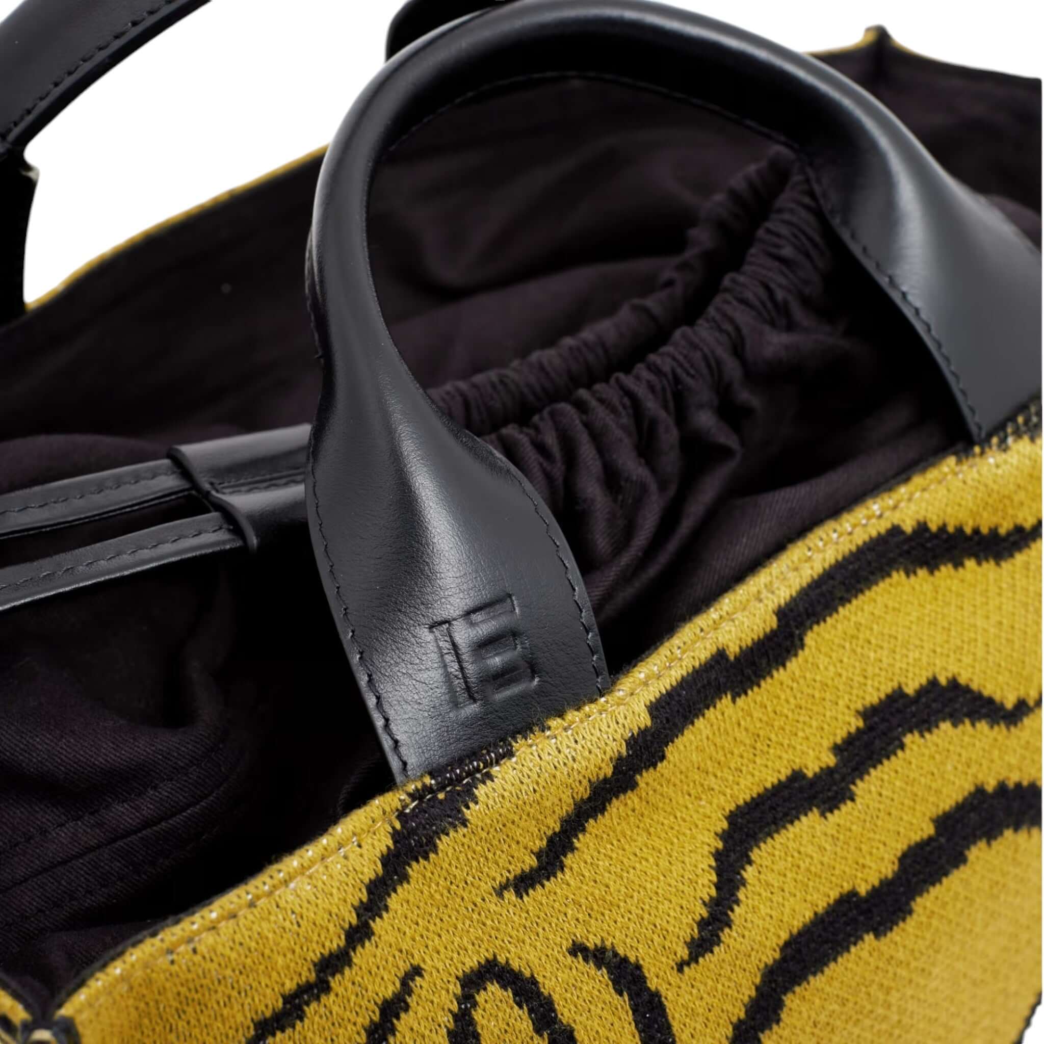 Dettaglio della Borsa a Tracolla Nomade Baldo Kaki con manici in pelle e design a strisce gialle.