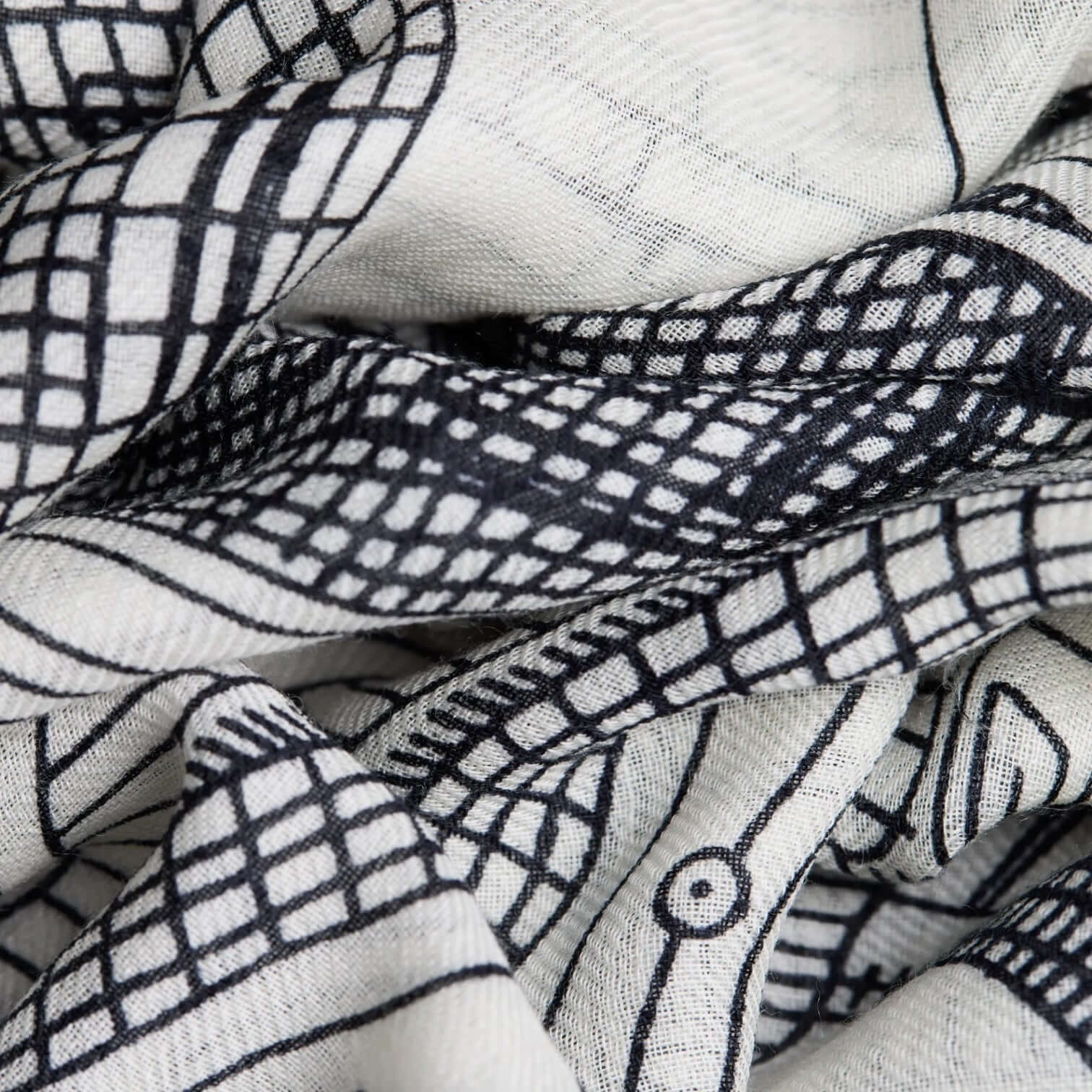 Close-up of the Sciarpa Paris Bianco, featuring creative black and white designs on lightweight fabric.