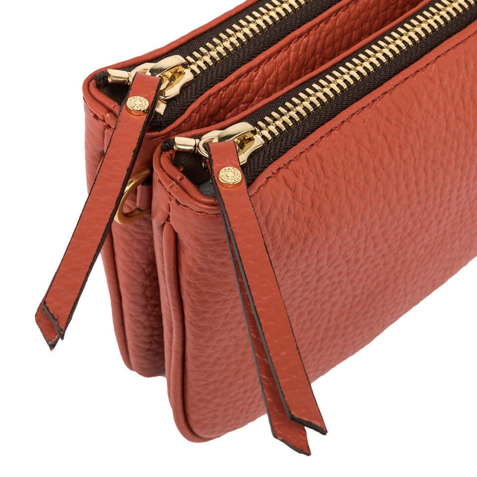 Close-up of the Frida handbag with two gold zippers and textured leather in a warm color.