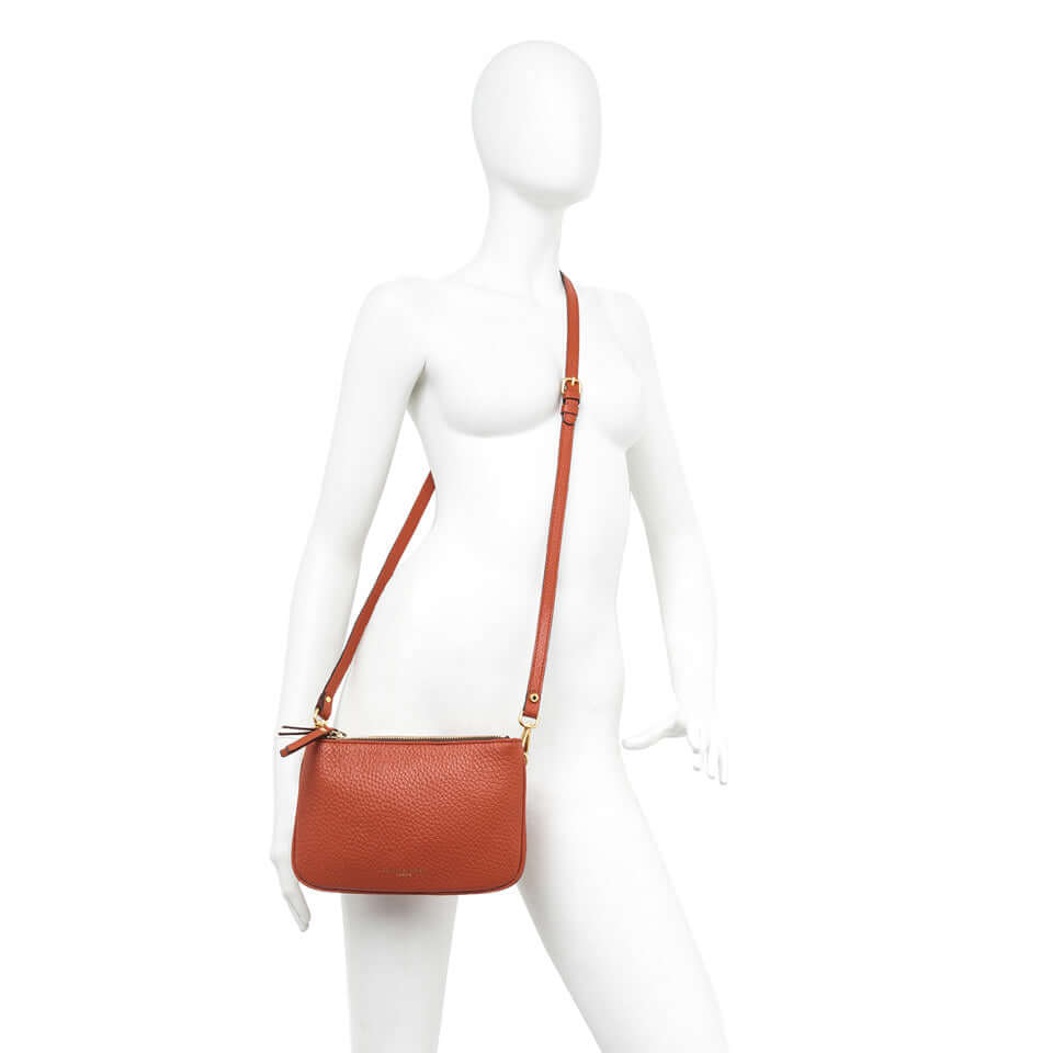 Frida leather crossbody bag in terracotta, featuring two zippers and a removable adjustable strap.
