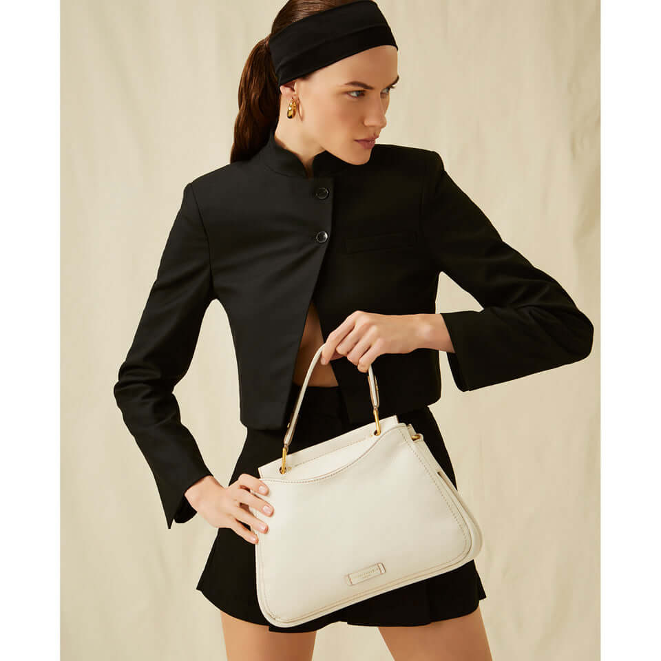 Model wearing a chic black outfit holding the MAREA handbag, showcasing its elegant design and versatility.