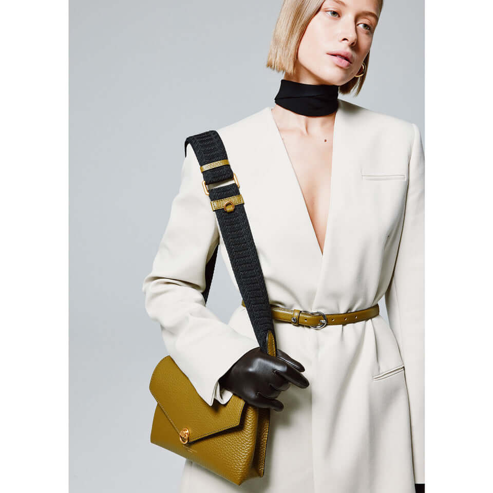 Model wearing a stylish white blazer with a chic mini bag in olive green, showcasing versatility and trendy fashion.