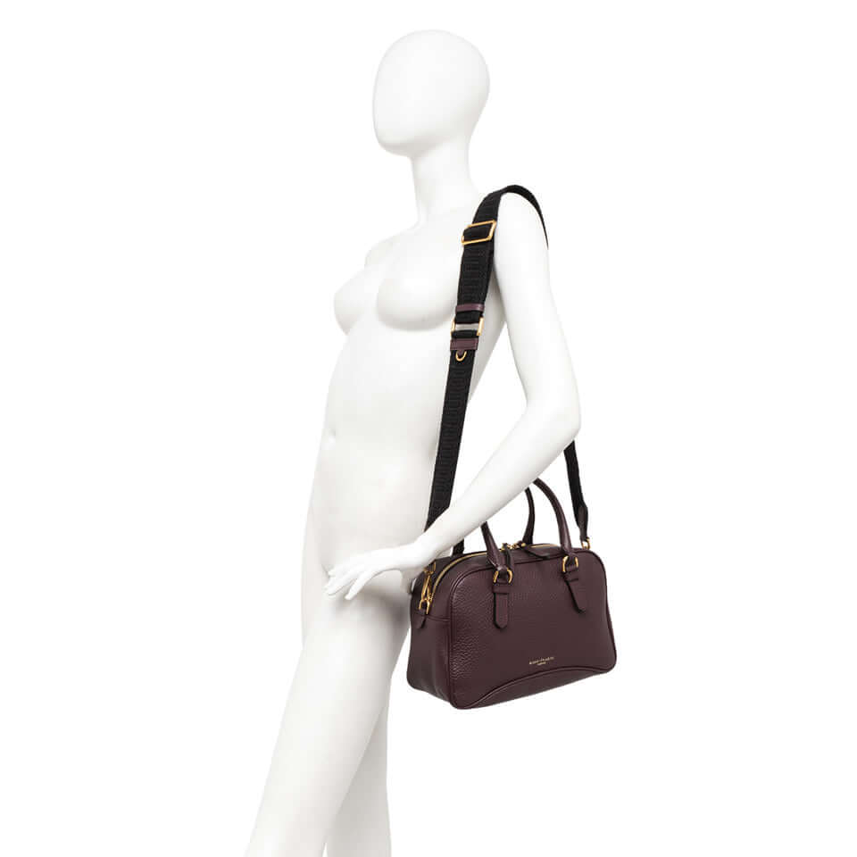 Chiara vintage-style leather bag in deep burgundy with removable cross-body strap on mannequin.