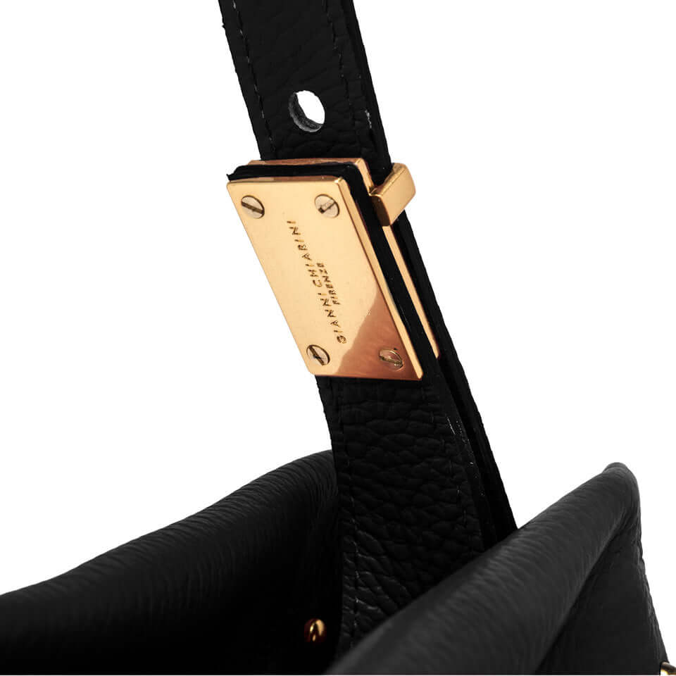 Close-up of the golden logo detail on the black leather strap of the Matilde shoulder bag.