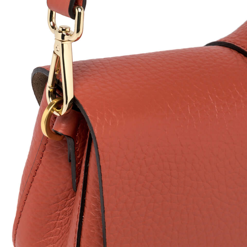 Close-up of the orange leather strap of the Gianni Chiarini Helena Round bag with gold hardware.