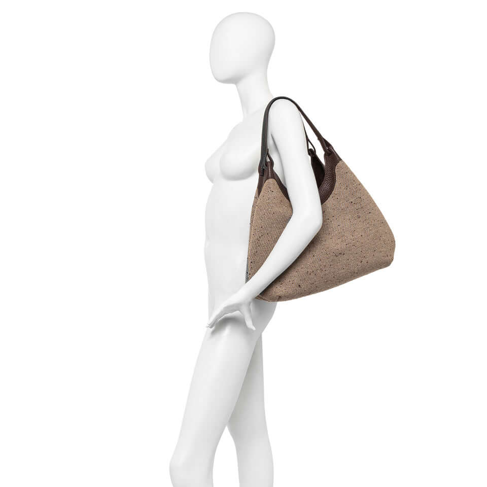 Borsa DUA in tessuto lana intrecciato con manici in pelle, indossata a spalla su manichino.