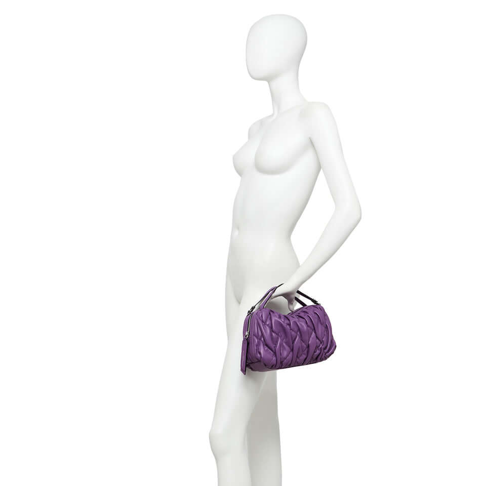 Elegant purple handbag with double handles, showcased on a mannequin, emphasizing its compact and stylish design.