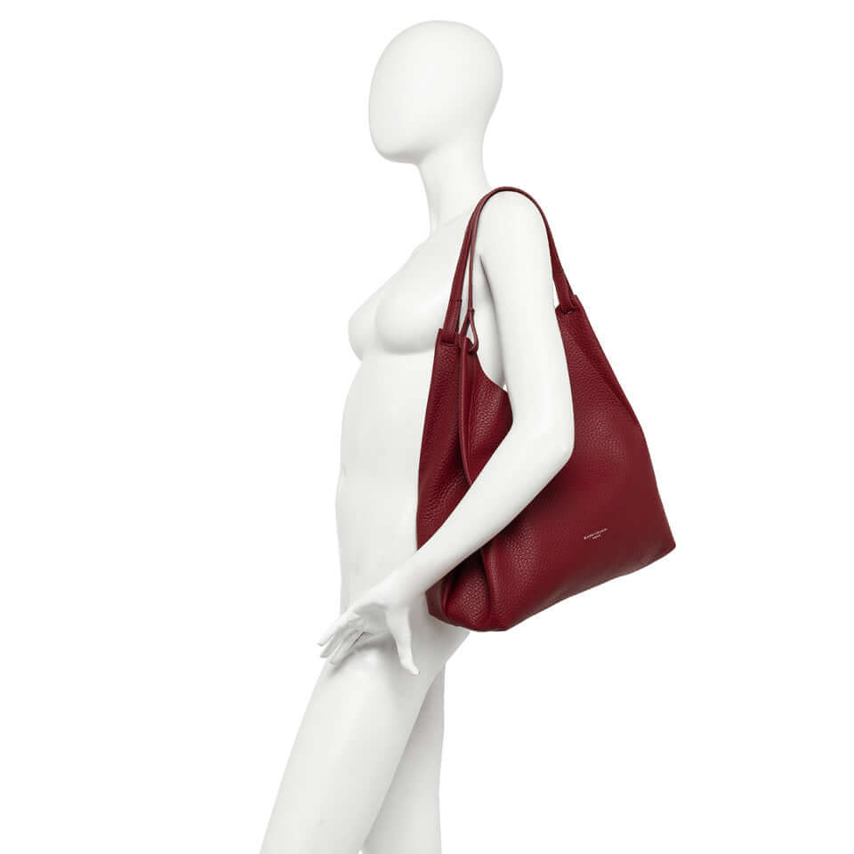 Elegant DUA handbag in red double-grain leather, showcasing a versatile design and practical features.