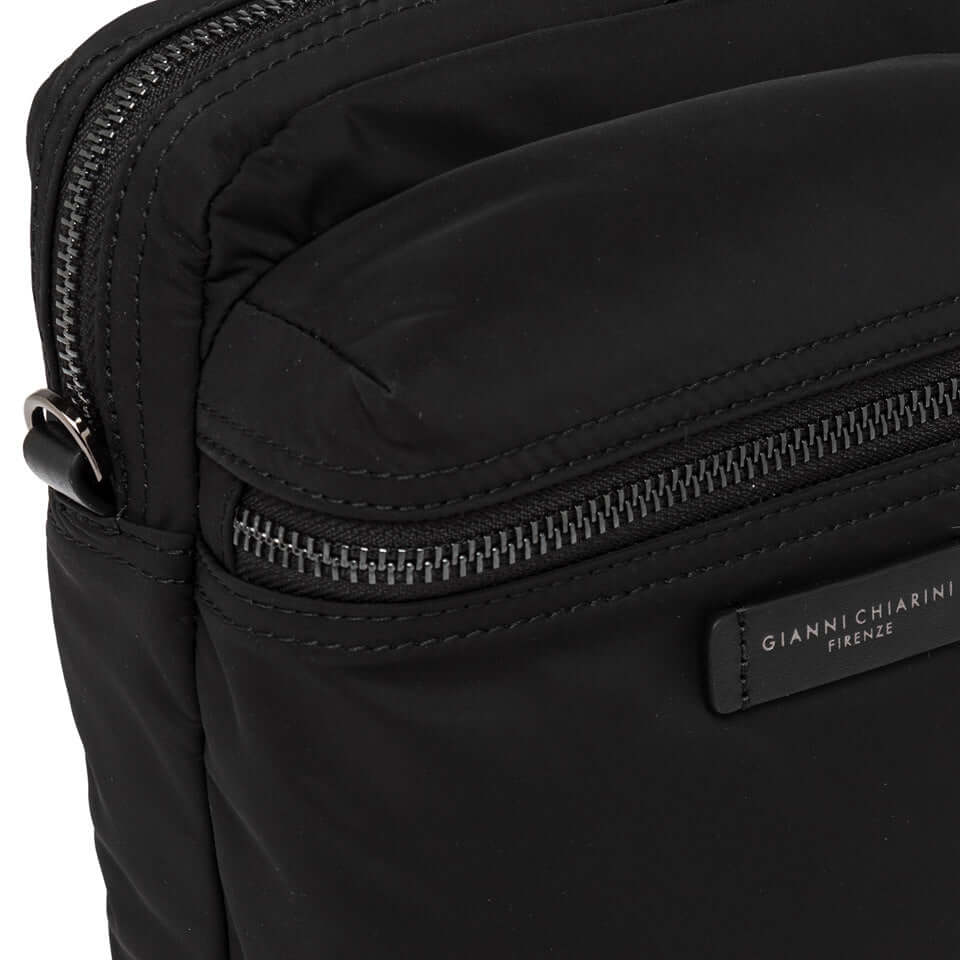 Close-up of black nylon Oslo crossbody bag with zippered compartments and leather accents.