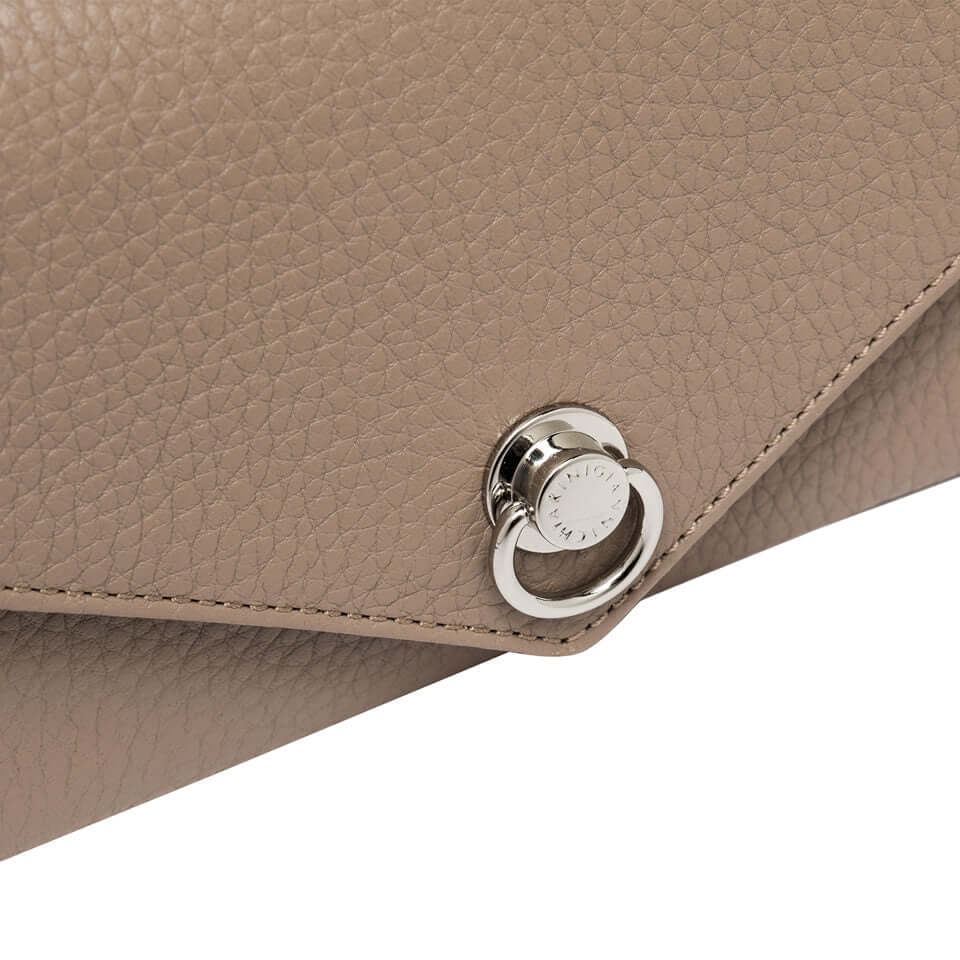 Close-up of the Deva bag's textured leather and iconic piercing detail in a stylish taupe color.