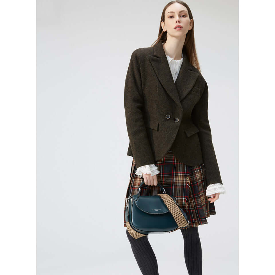 Model wearing a stylish blazer and plaid skirt, holding the Grace bag in green, showcasing its versatile design.