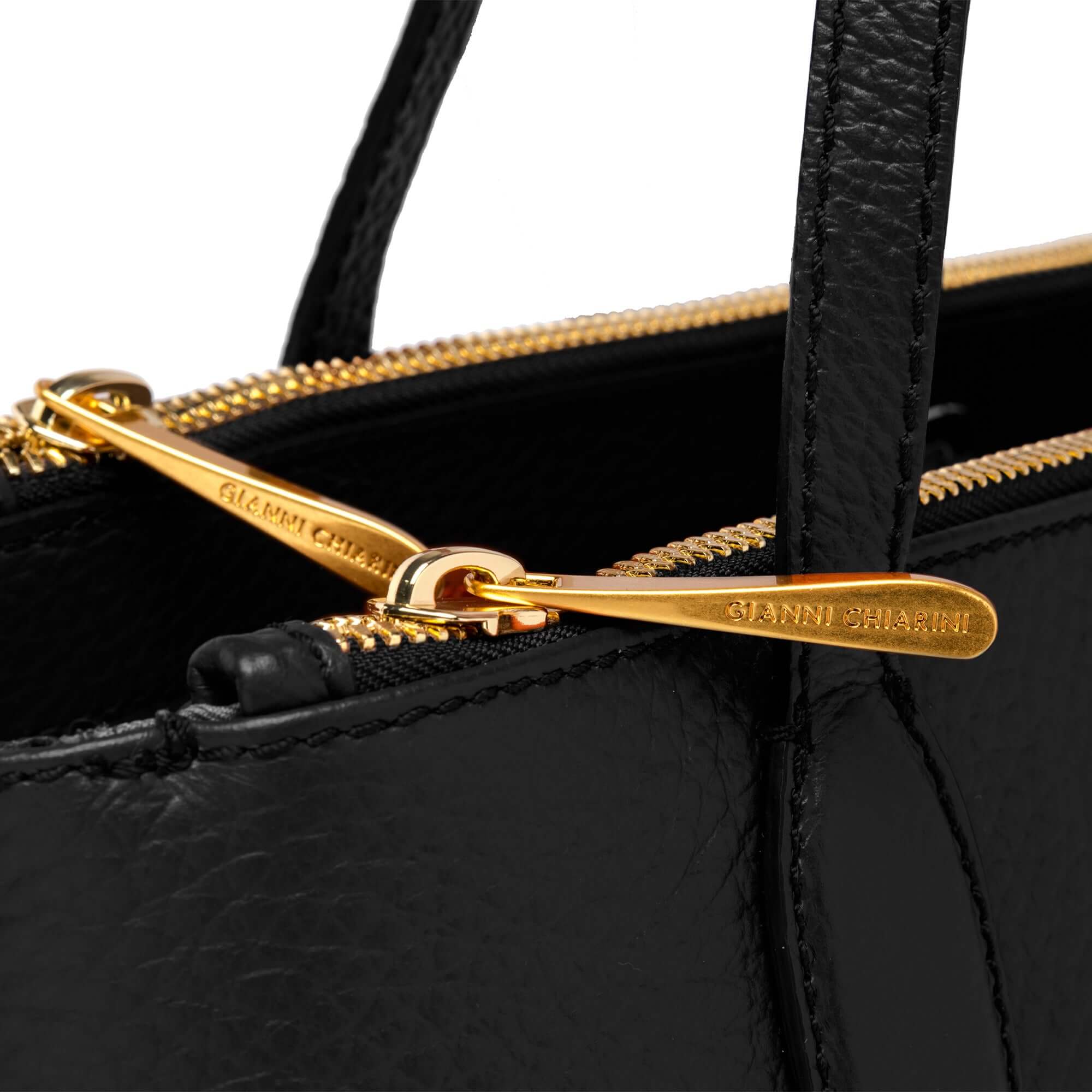 Close-up of the elegant black Mara shopping bag with gold double zip, showcasing premium leather and embossed logo.