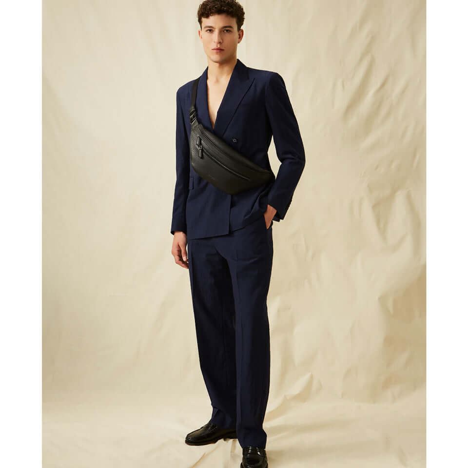 Man in a navy suit wearing the FLORENCE black leather marsupio for a stylish daily look.