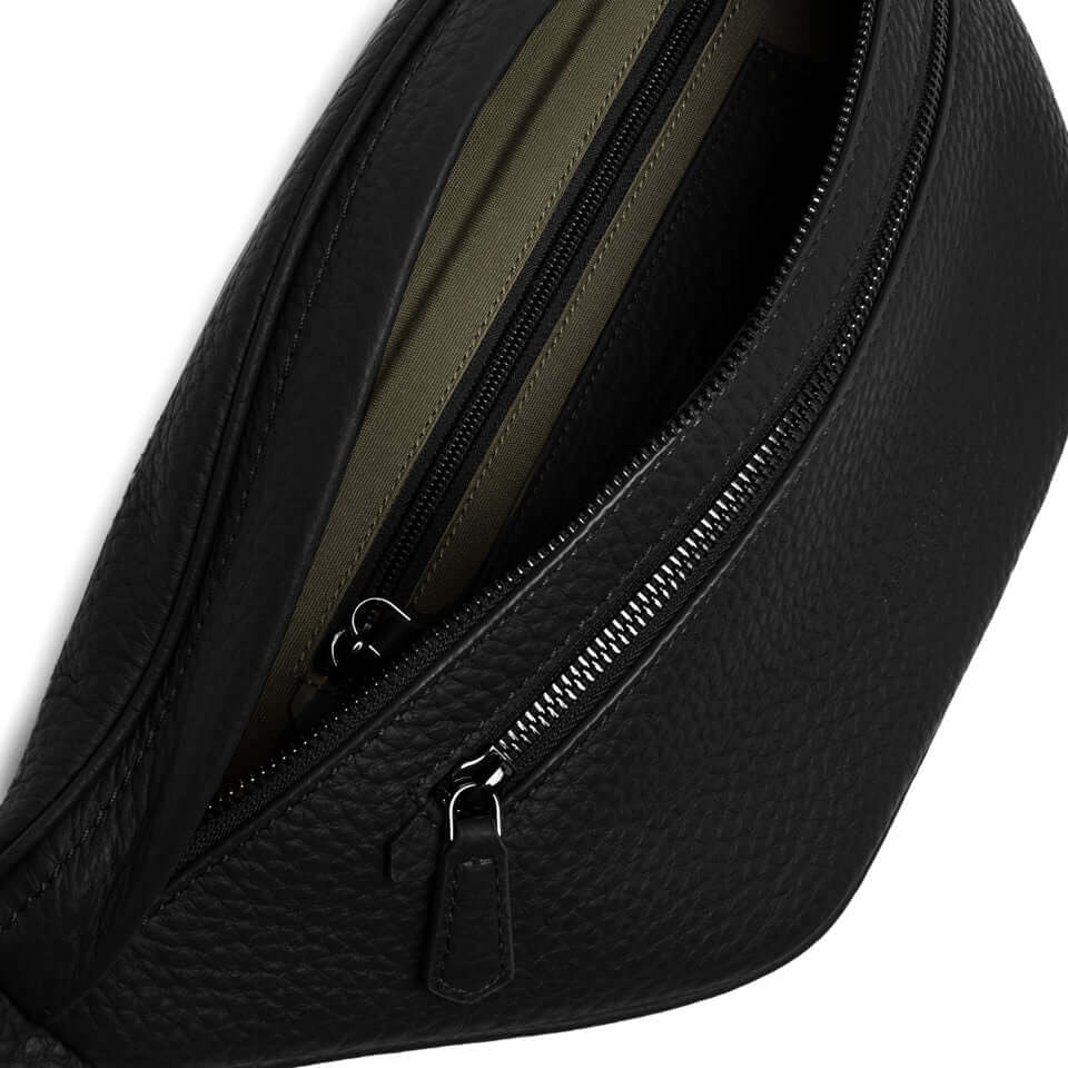 Close-up of FLORENCE marsupio, featuring zippered compartments and textured black leather interior.