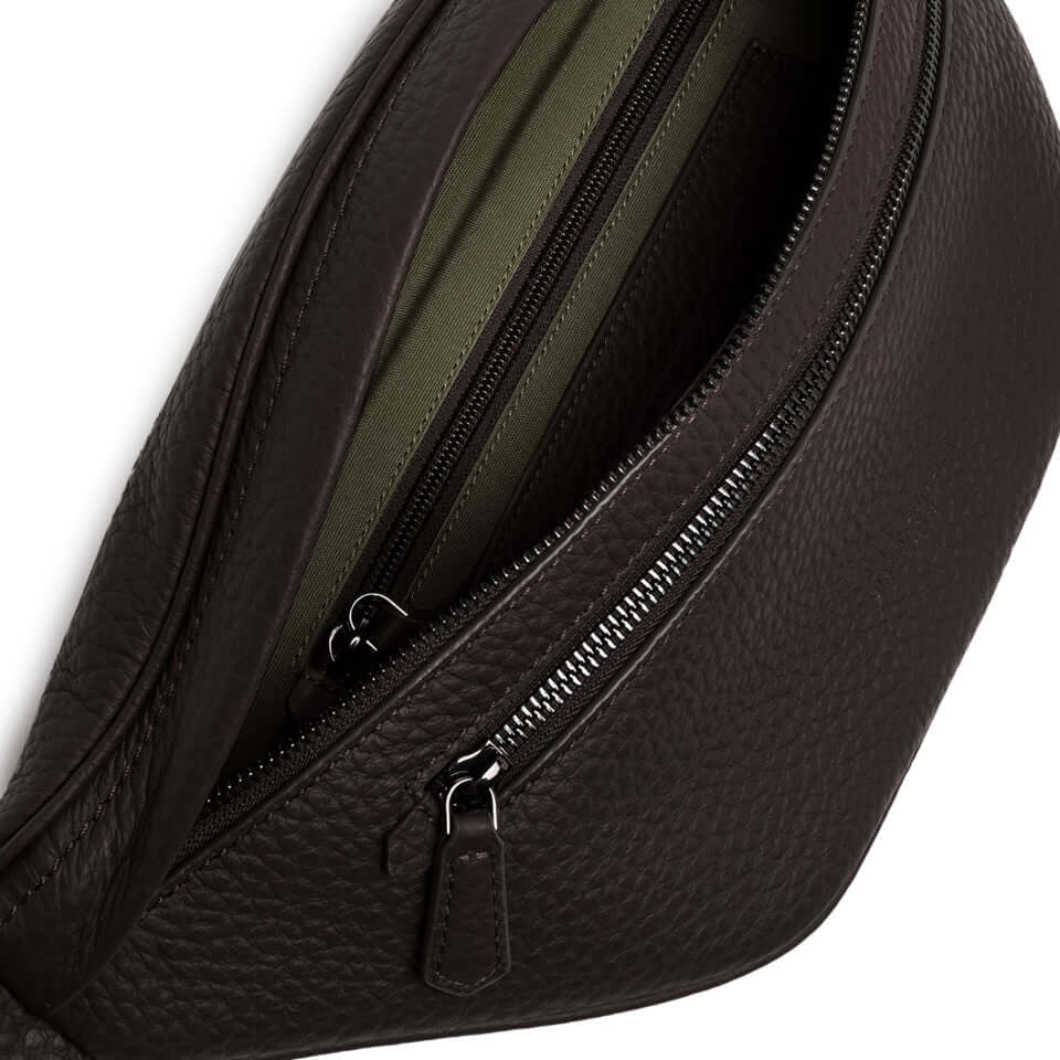 Close-up of the interior of a dark brown leather FLORENCE marsupio, featuring zip compartments and a sleek design.
