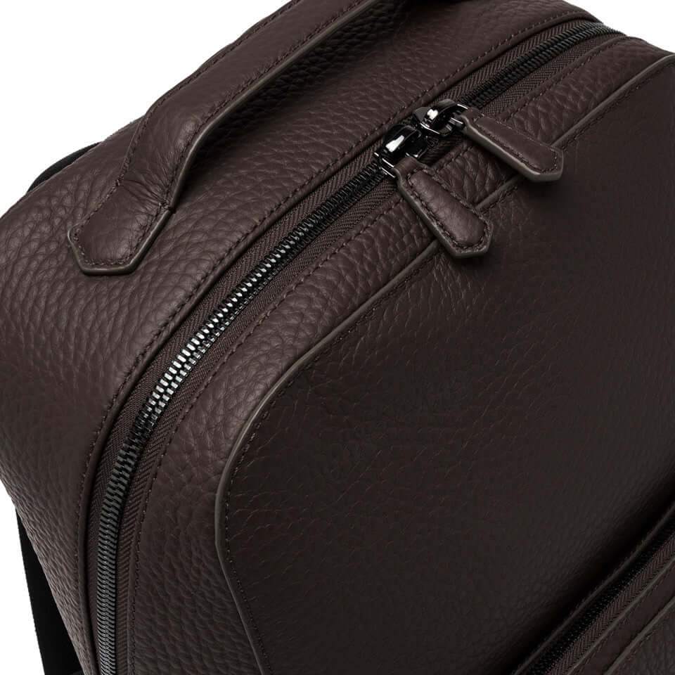 Brown textured leather backpack with zippers, showcasing a minimalist design and functional details.
