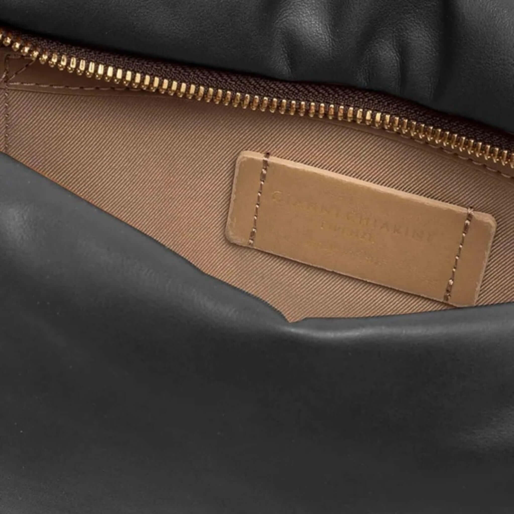 Close-up of the interior zipper and label of the black Allegra clutch by Gianni Chiarini Firenze.