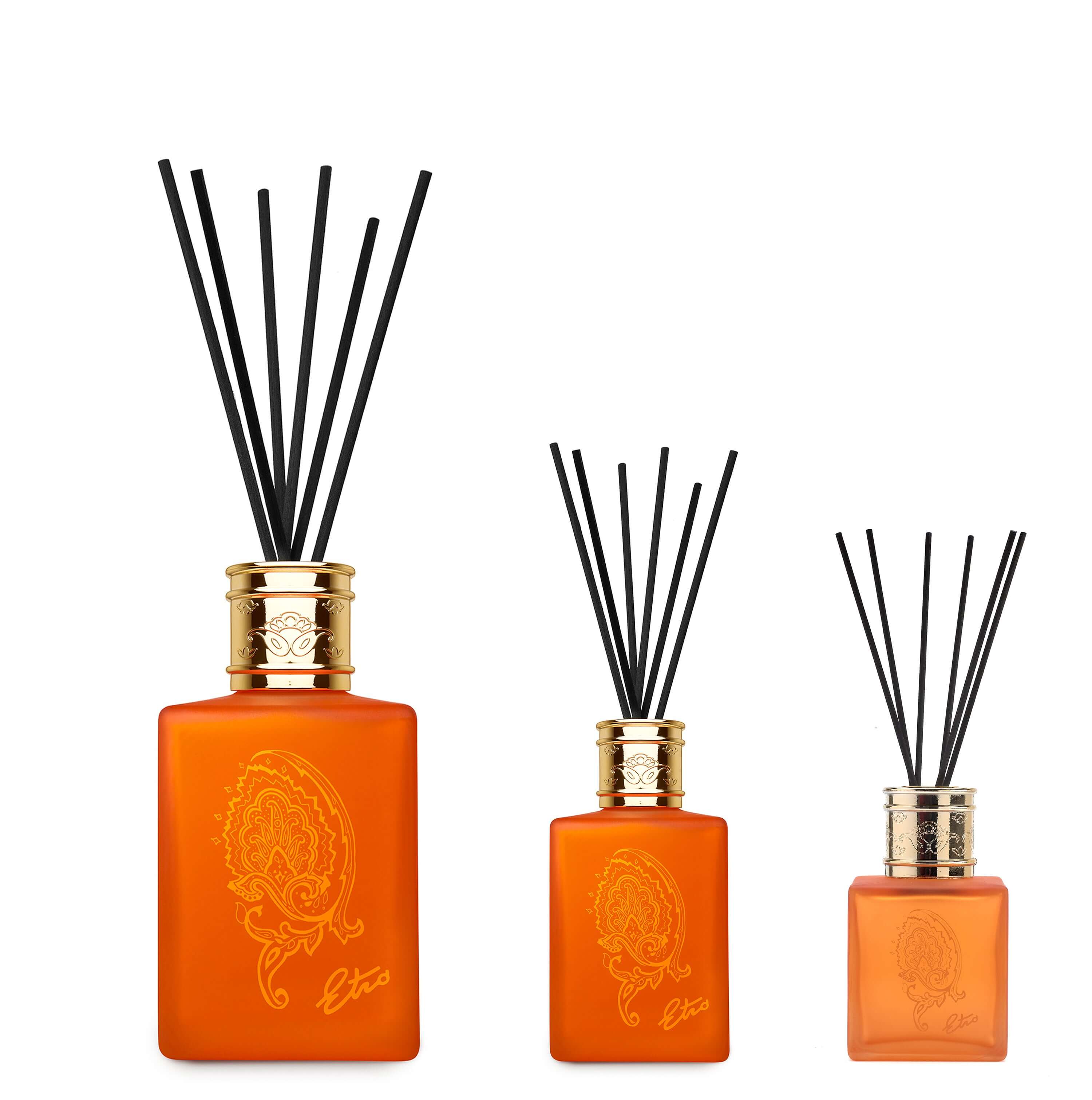 Elegant Eos Diffusore set with orange glass bottles and black reeds, showcasing different sizes and paisley decor.