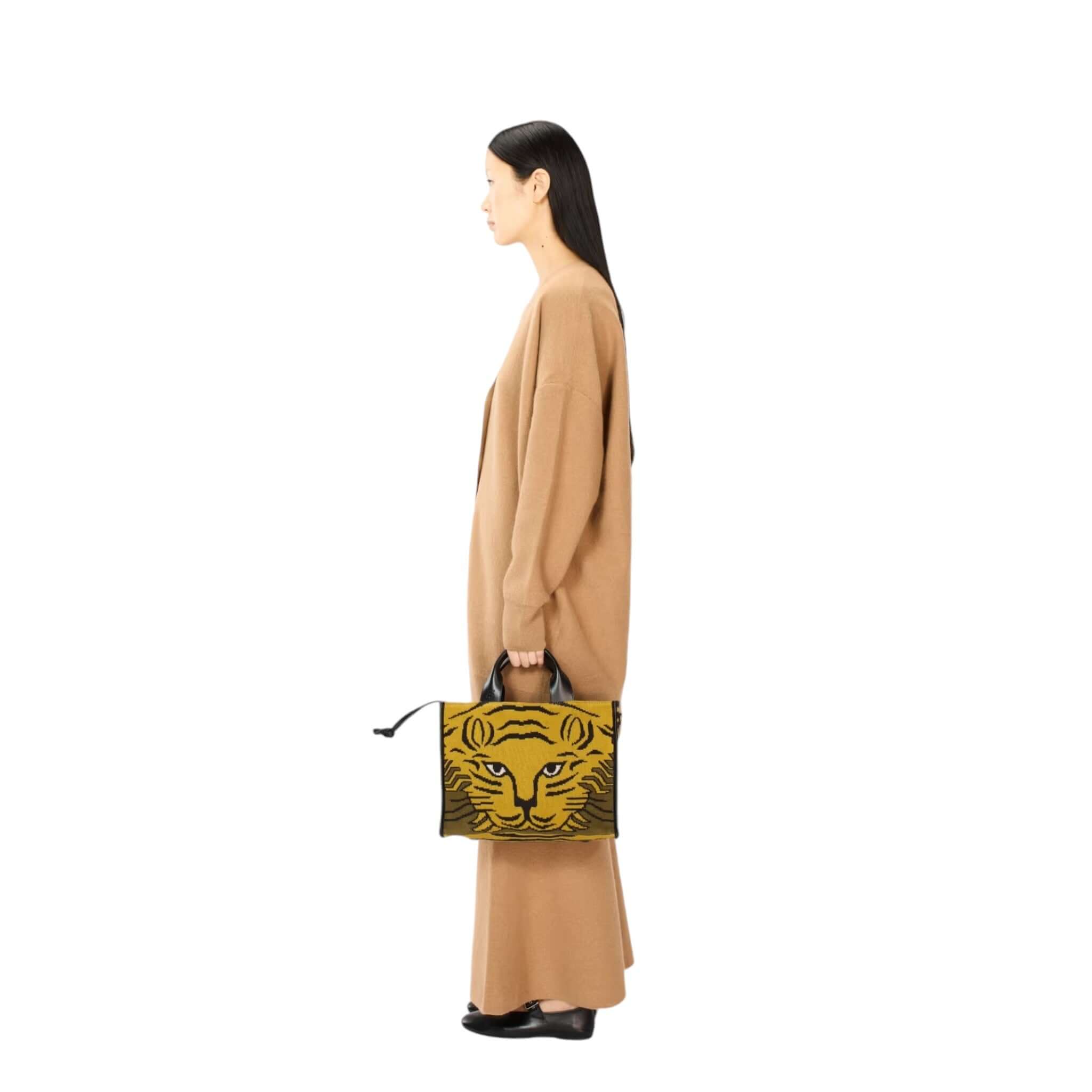 Woman in brown outfit holding a tiger print handbag, showcasing a stylish side profile view.