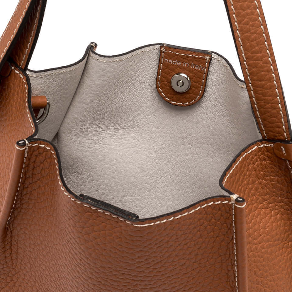 Dory bag interior showcasing leather texture and magnetic closure, highlighting made in Italy craftsmanship.