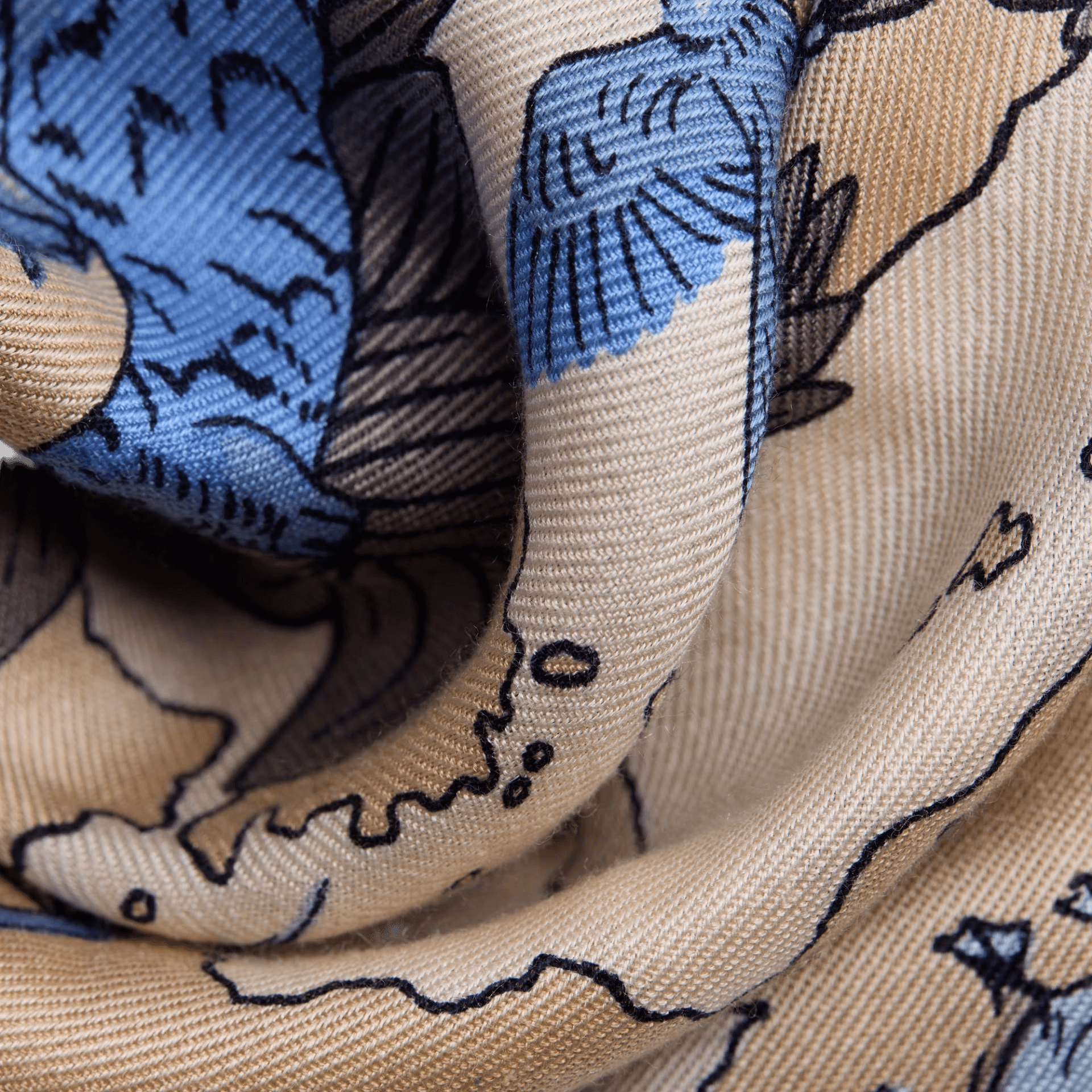 Foulard quadrato in seta con design artistico in blu e beige, dettaglio di un tessuto elegante e versatile.