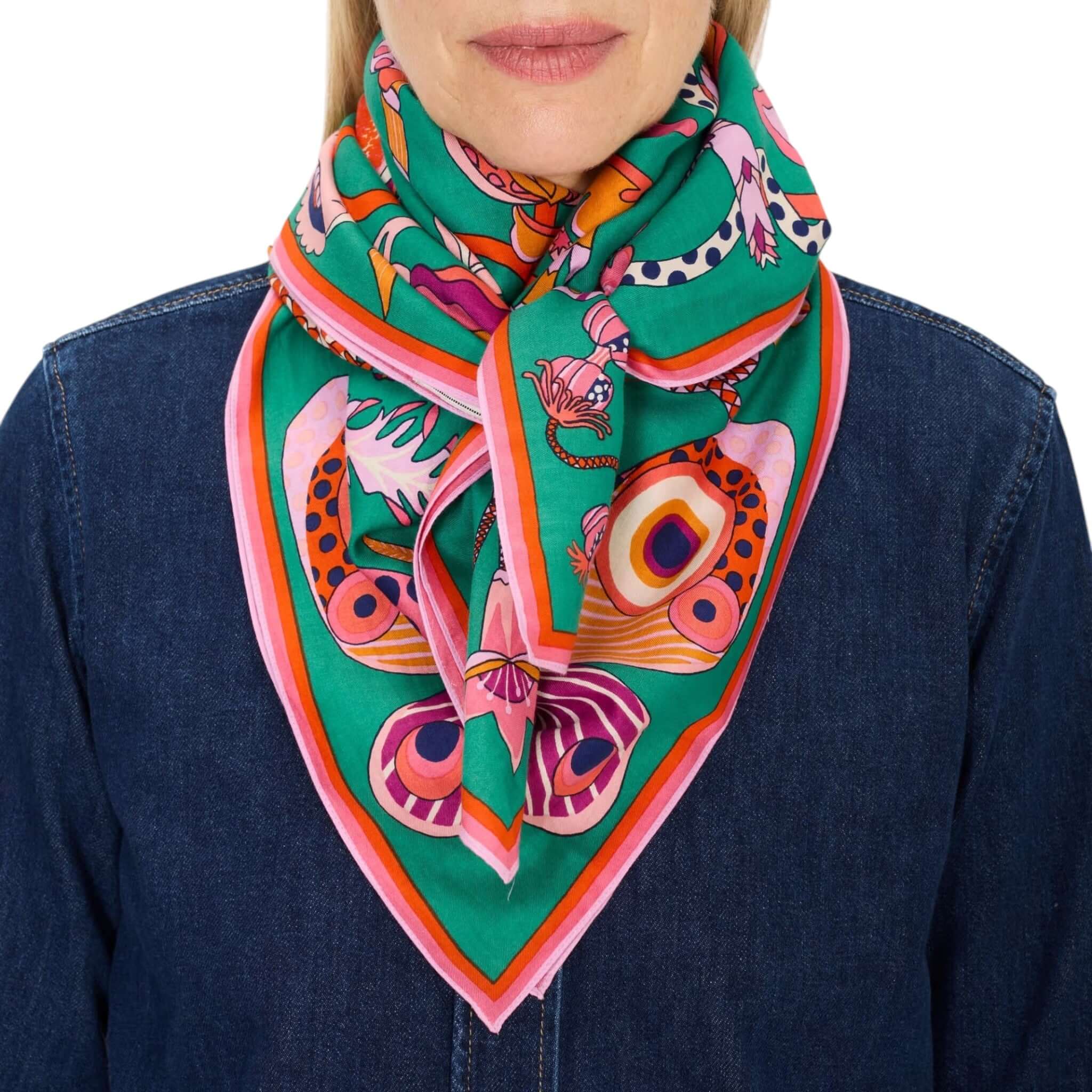 Foulard Quadrato Botanique indossato, con design floreale su sfondo verde, perfetto per capelli o come accessorio al collo.