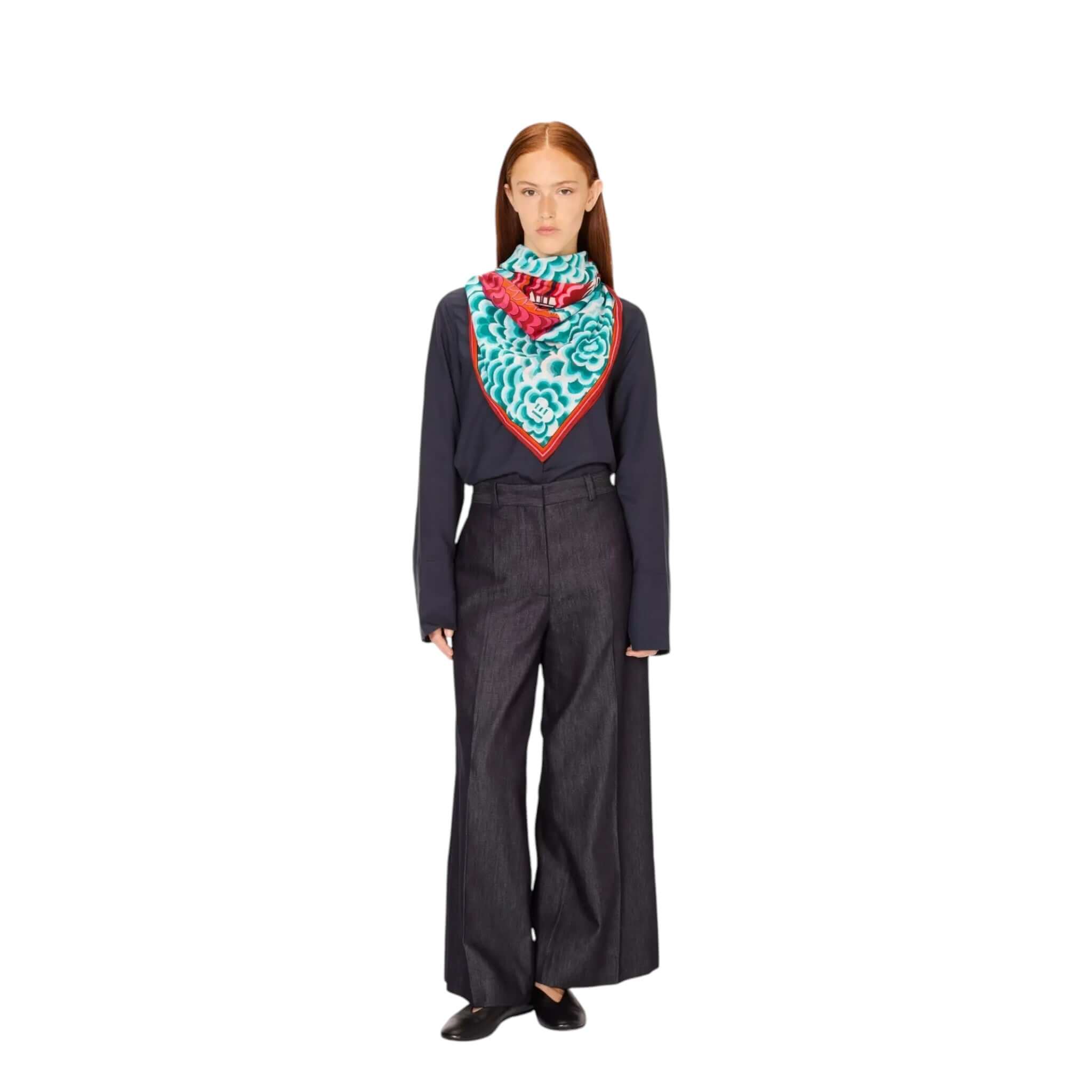 Model wearing a blue and red hand-printed Foulard Quadrato Dragon styled as a scarf with a chic outfit.