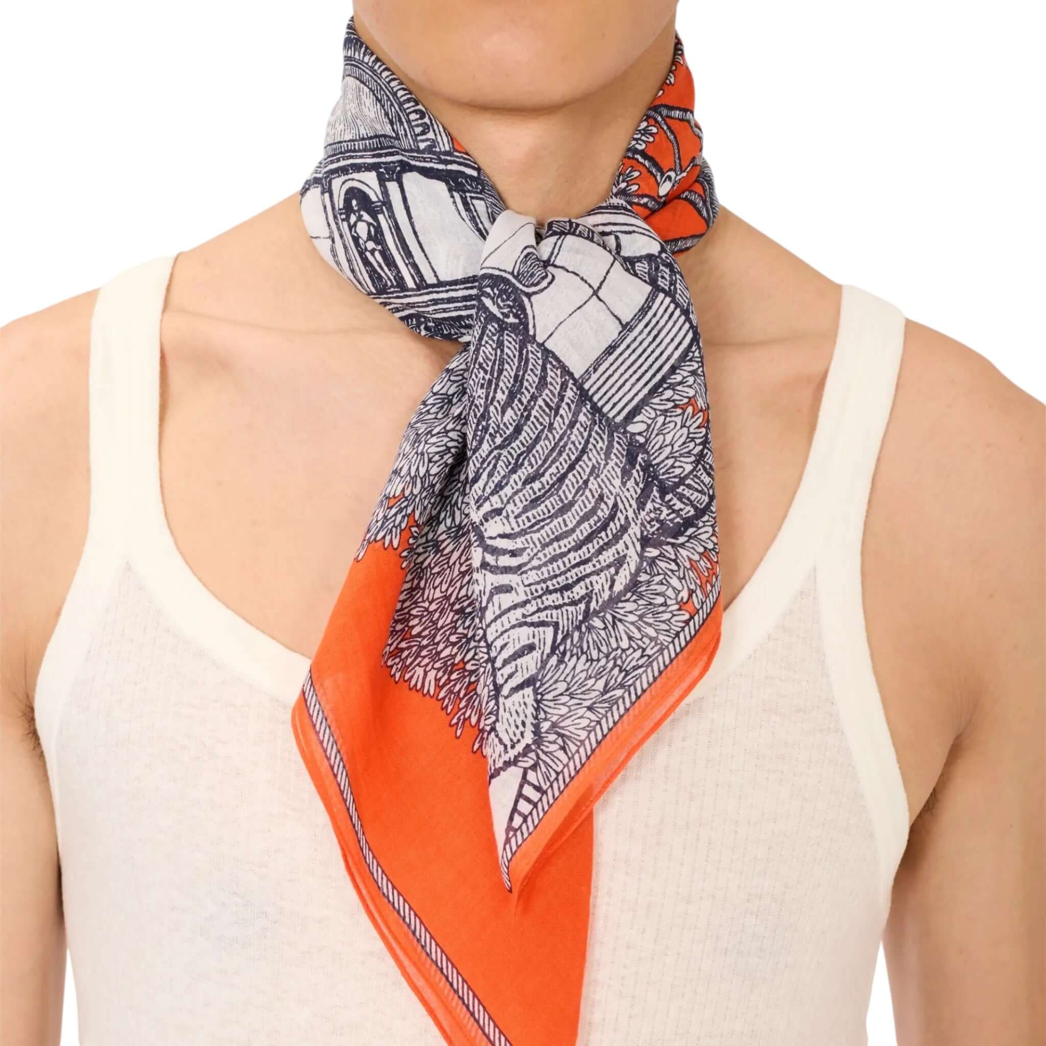 Foulard Quadrato Mirage indossato, con disegni artigianali in bianco e arancione, ideale per ogni occasione.