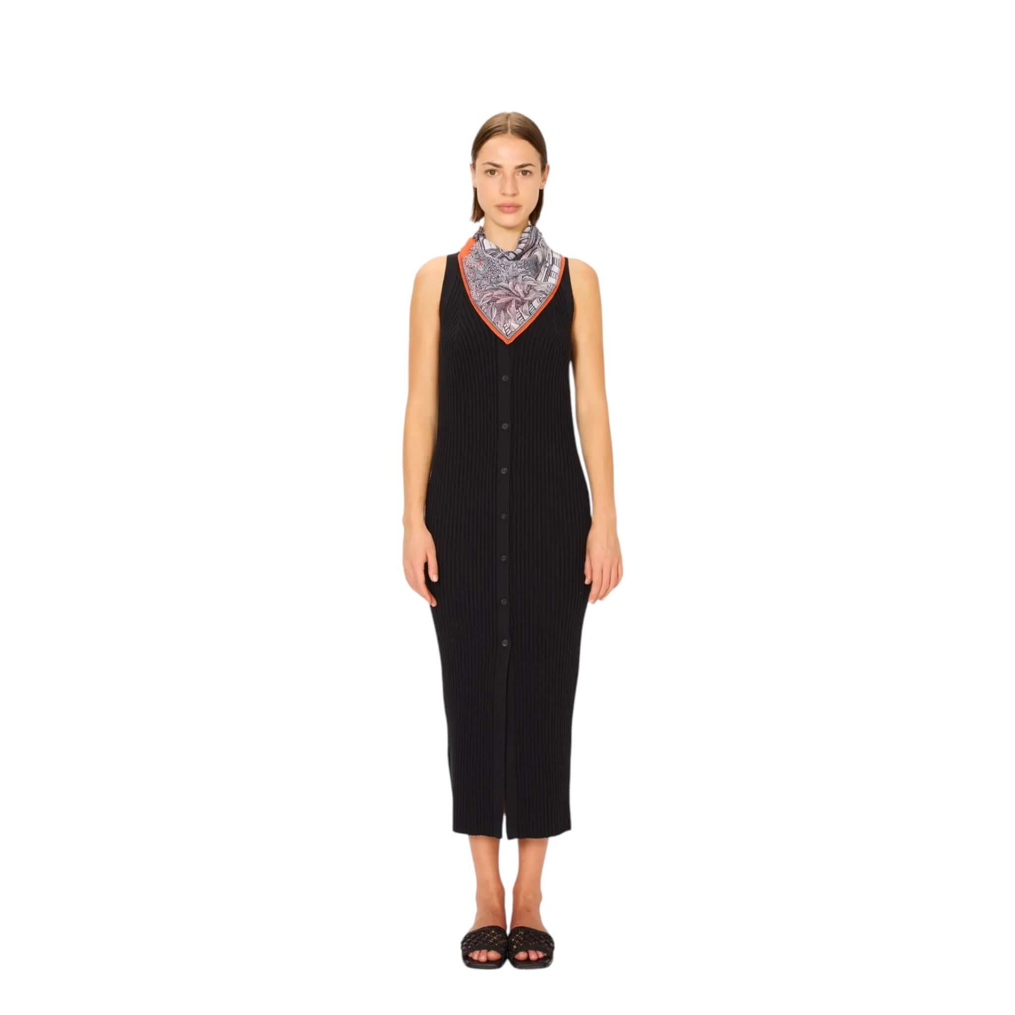 Woman wearing a black dress paired with a Foulard Quadrato Mirage scarf featuring a colorful print.