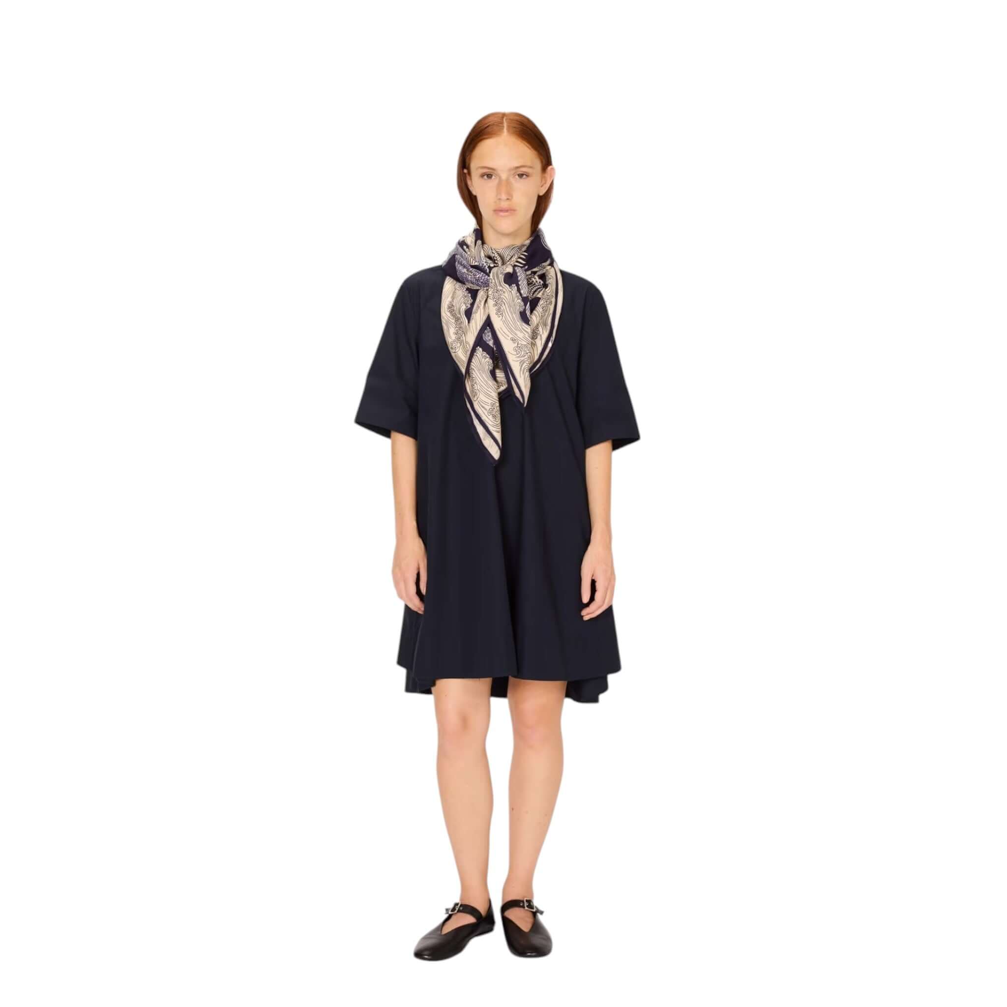 Woman in a dark dress wearing the Foulard Quadrato Poseidon, featuring a unique modal silk design.
