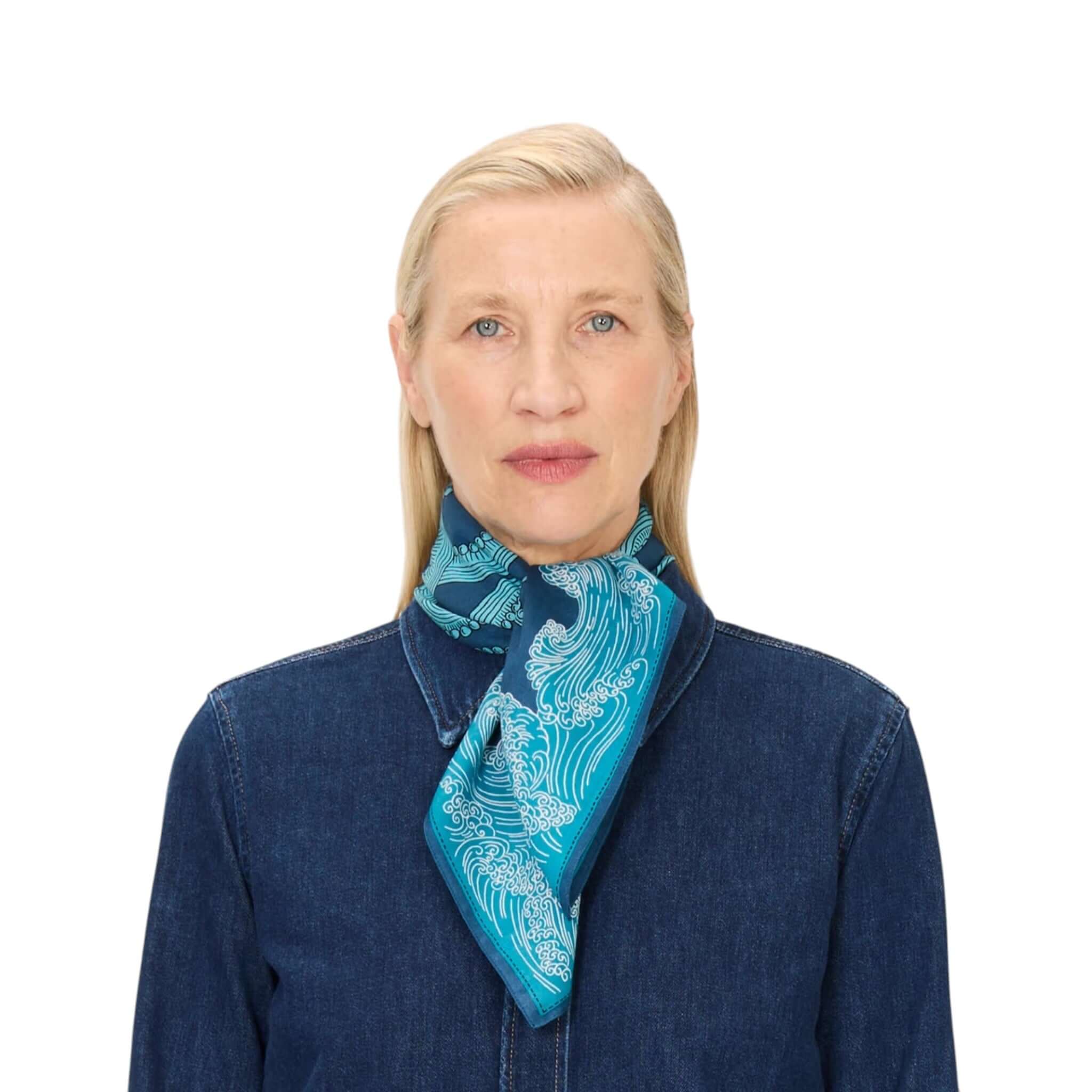 Foulard Quadrato Poseidon in seta, blu e bianco, indossato come sciarpa da donna elegante.
