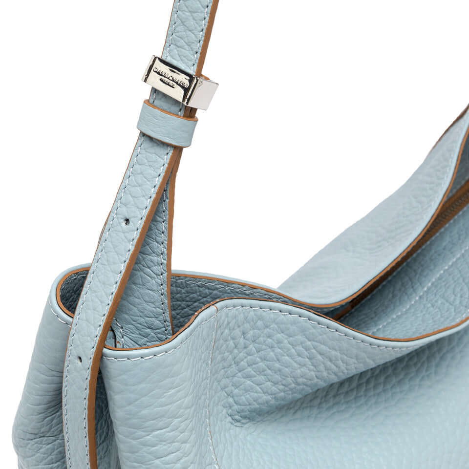 Close-up of Minerva handbag by Gianni Chiarini Firenze in soft blue leather with magnetic closure and shoulder strap.