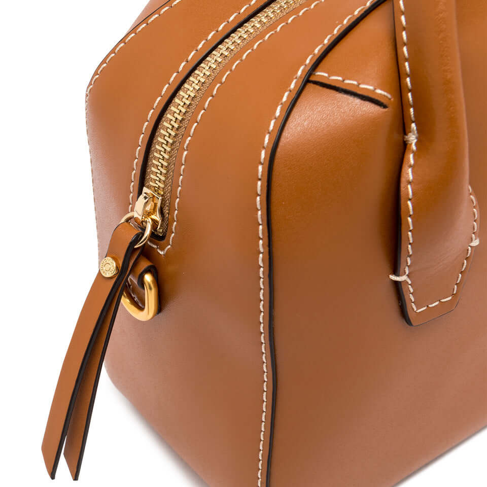 Close-up of Sabrina small bowling bag in smooth brown leather, featuring gold zipper and double handles.