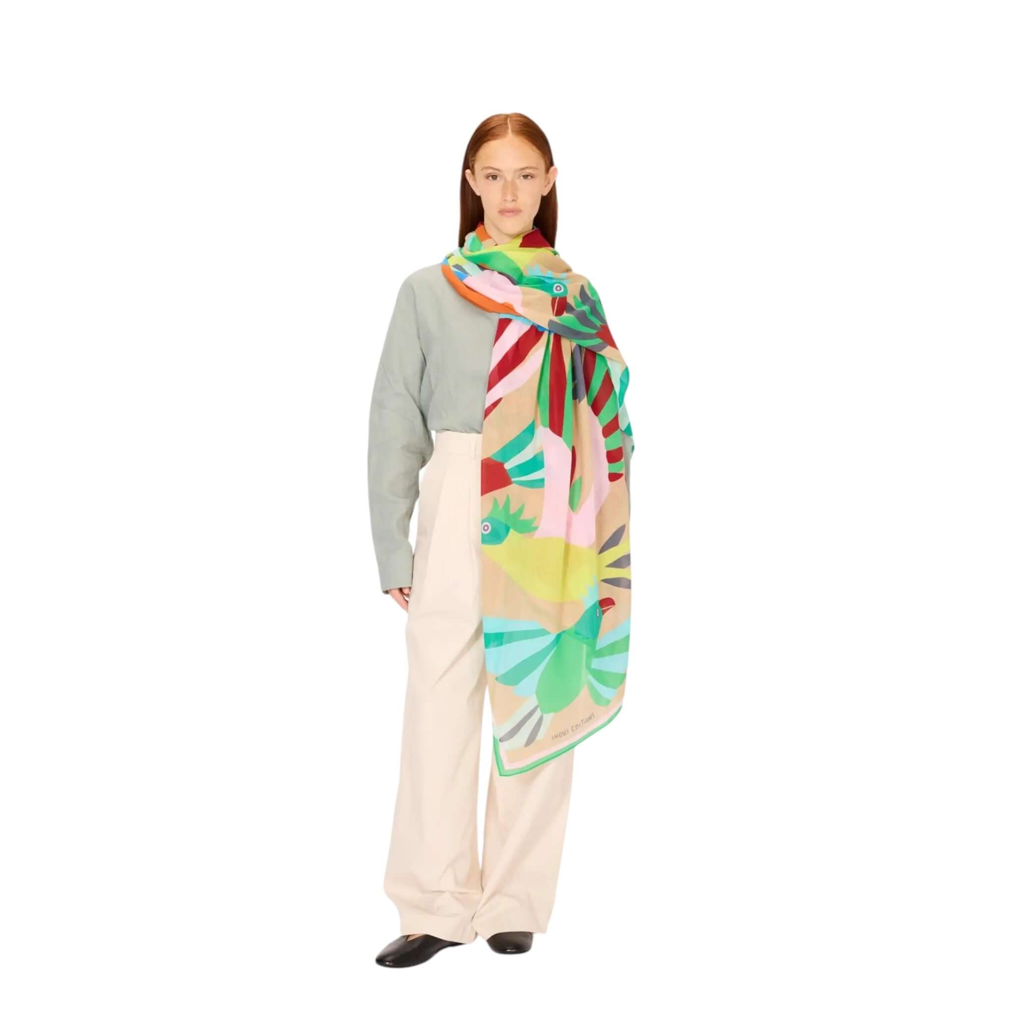 Modella indossa la sciarpa Voyage, un accessorio estivo in cotone con design colorato e stampato a mano.