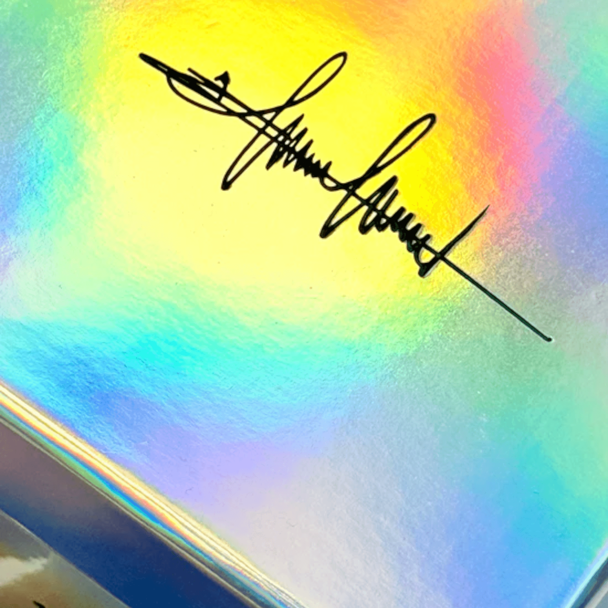 Signature on a holographic background, reflecting light in rainbow colors.