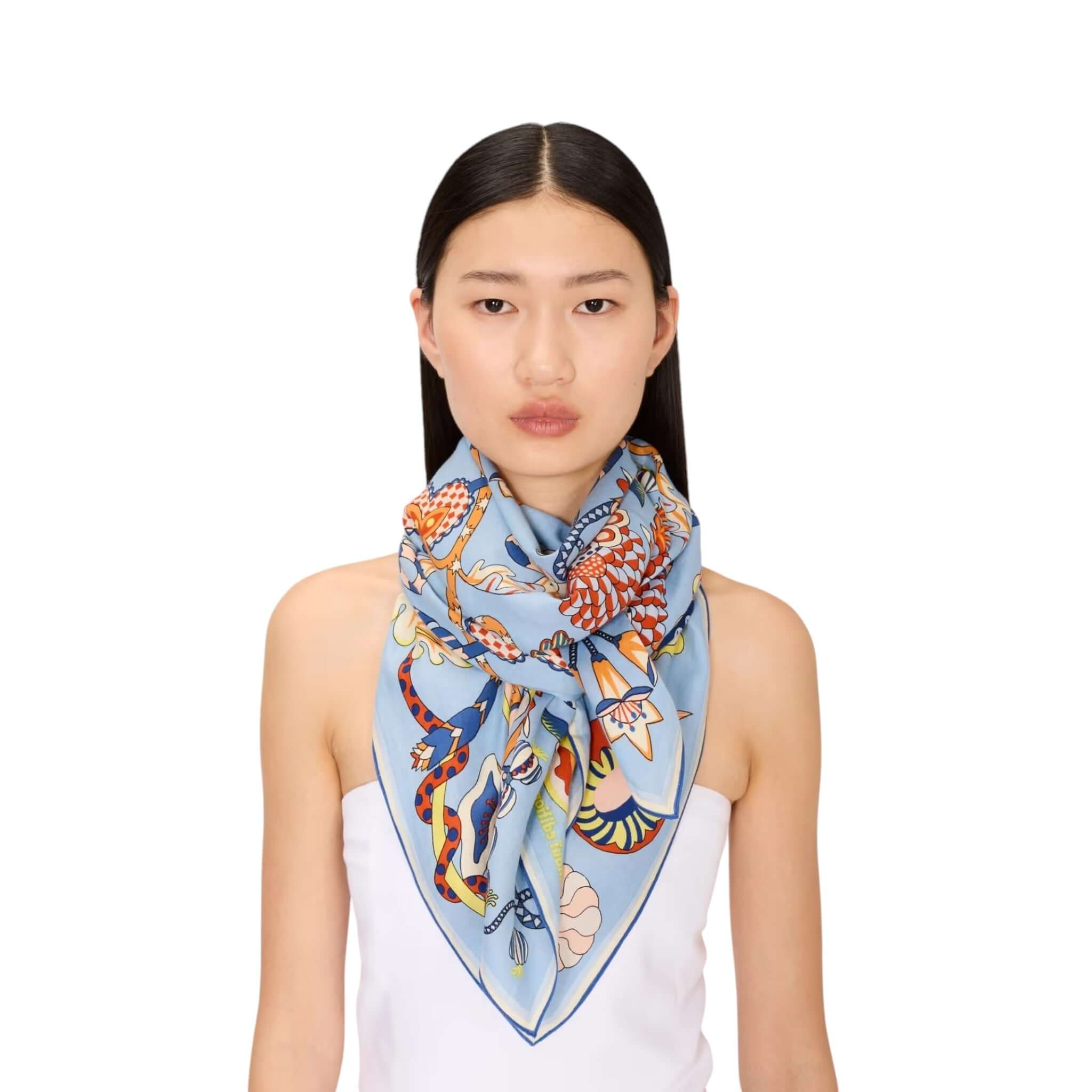 Foulard Quadrato Botanique indossato al collo da donna, in tessuto lucido stampato a mano con design floreale e colorato.