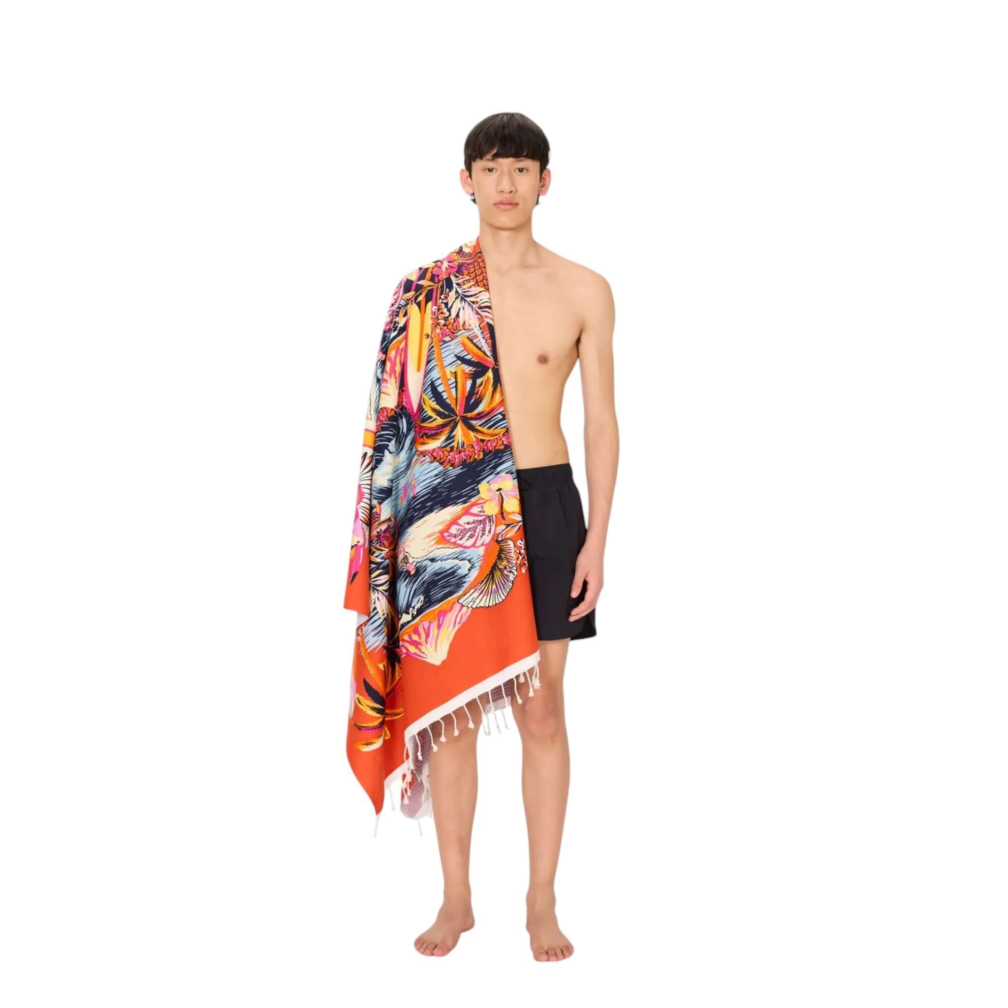 Young man wearing a vibrant hand-printed beach towel, showcasing Telo Mare Hawai design, perfect for summer.