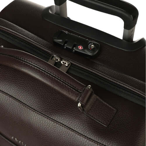 Dettaglio di un trolley in pelle marrone con chiusura di sicurezza e maniglia, realizzato in Italia.