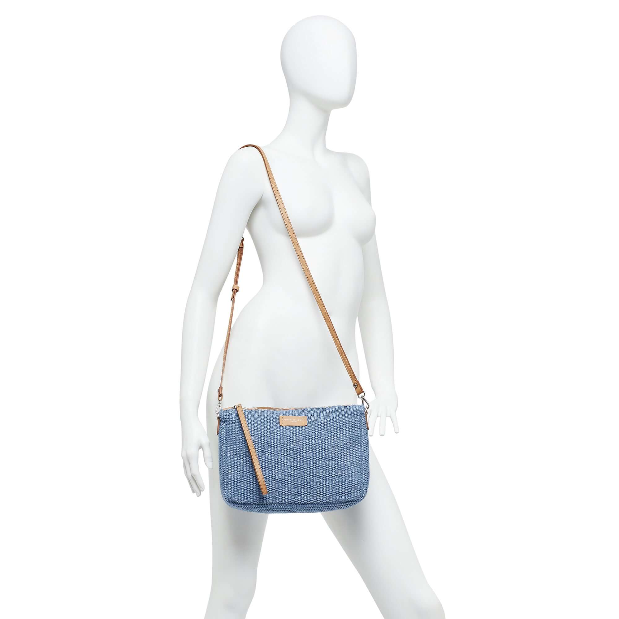 NORA POUCH in straw with smooth leather strap, zip closure, dimensions 28x21x9 cm, showcased on a mannequin.