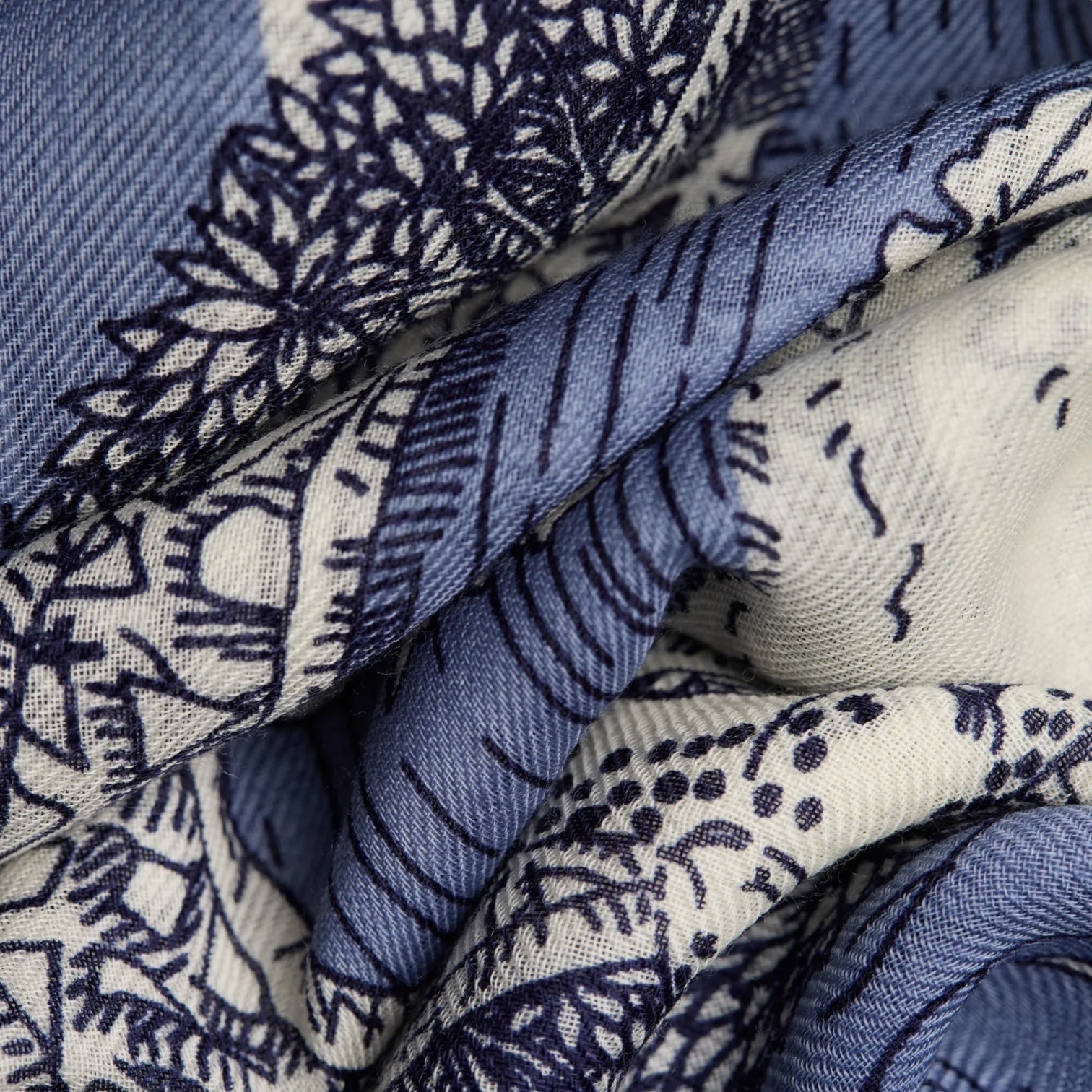 Detail of Sciarpa Quatre Saisons Blu, featuring creative designs in blue and white, ideal for adding color to your outfit.