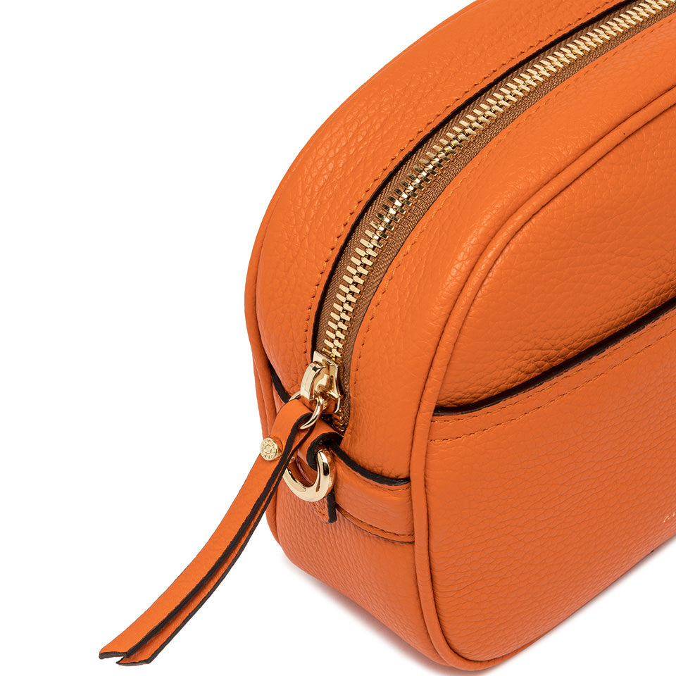 Close-up of the orange La Nina leather bag by Gianni Chiarini, showcasing its zip closure and textured surface.