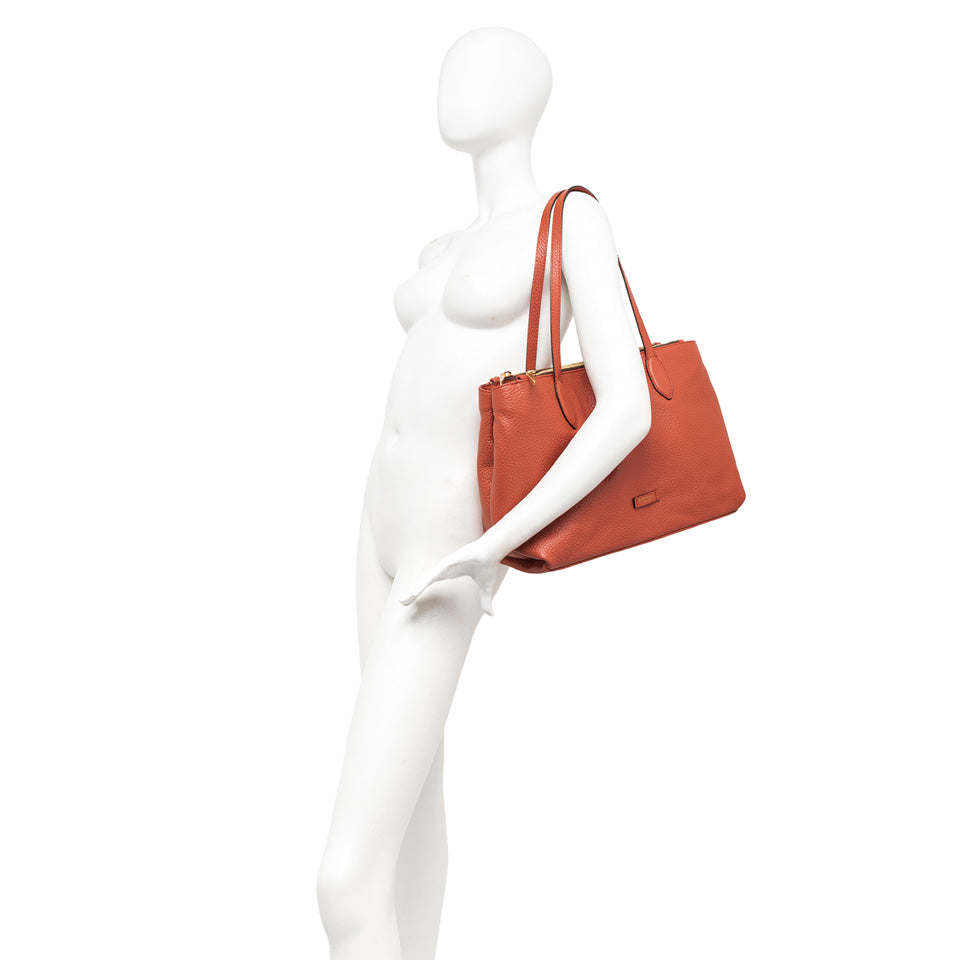 Elegante shopping bag Mara in pelle grana maxi, con chiusura a doppia zip e tre scomparti, indossata su manichino.