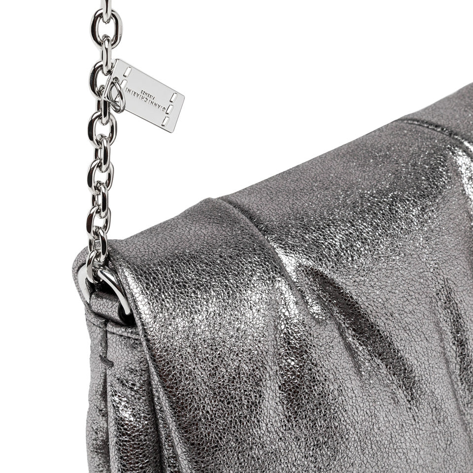 Close-up of GLENDA handbag in laminated leather, featuring a chain strap and magnetic button closure.