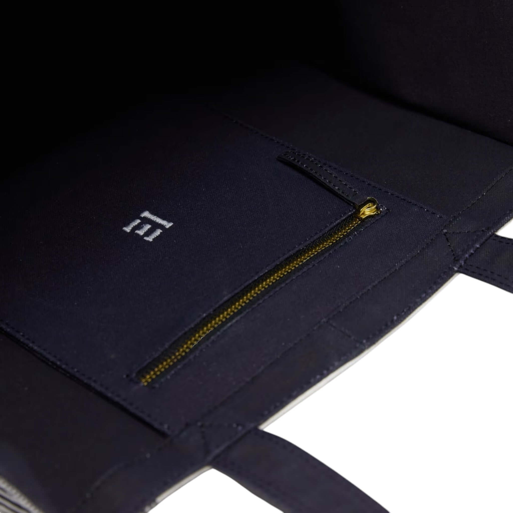 Interno della borsa tote Piranesi con tasca zip e logo, realizzata in cotone elegante e funzionale.