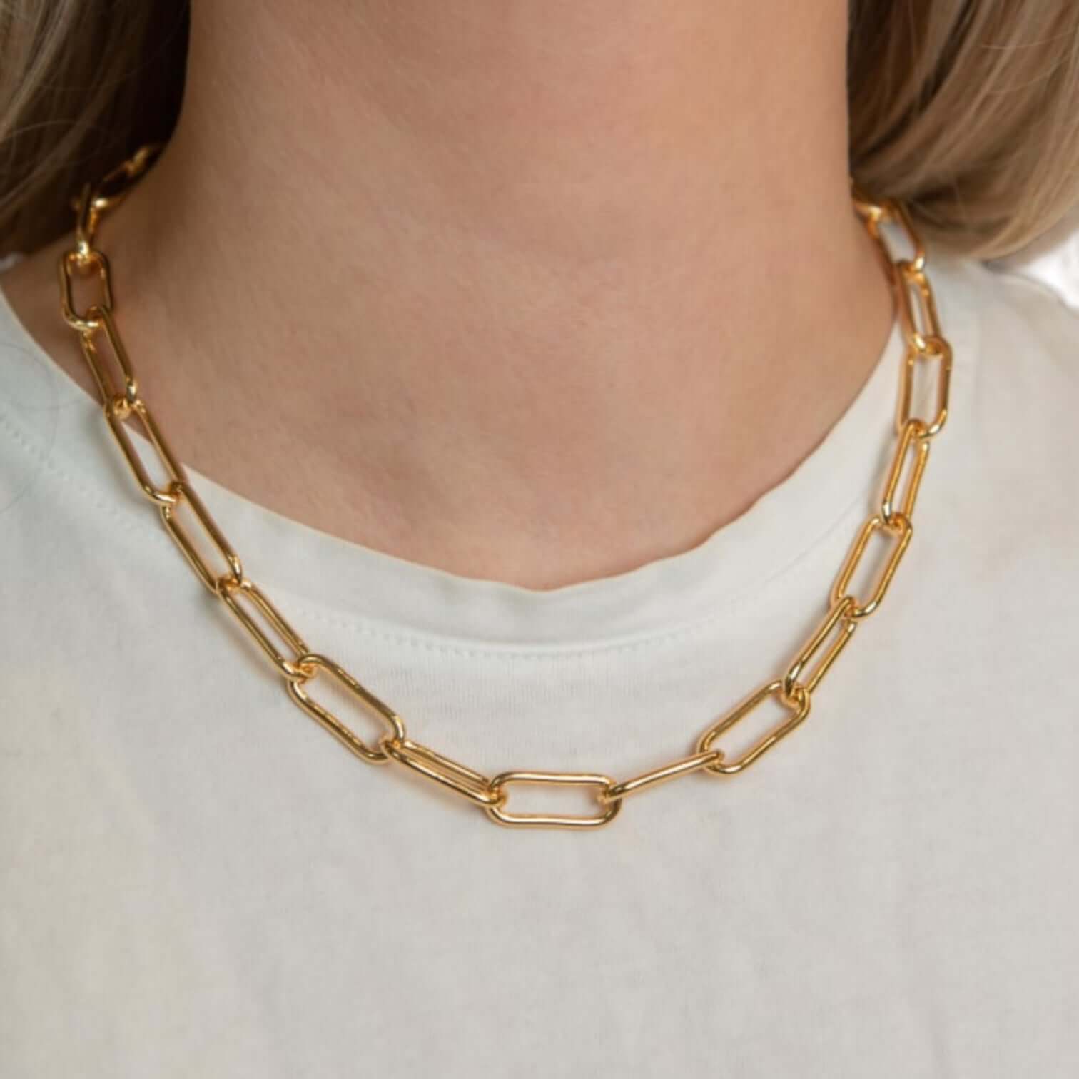 Collana La Catena in ottone placcato oro 18 carati, lunghezza 45 cm, indossata su una maglietta bianca.