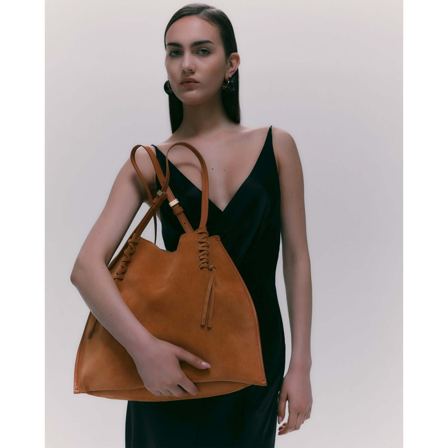 Model holding Dory bag in suede, showcasing its trendy design and versatile style.