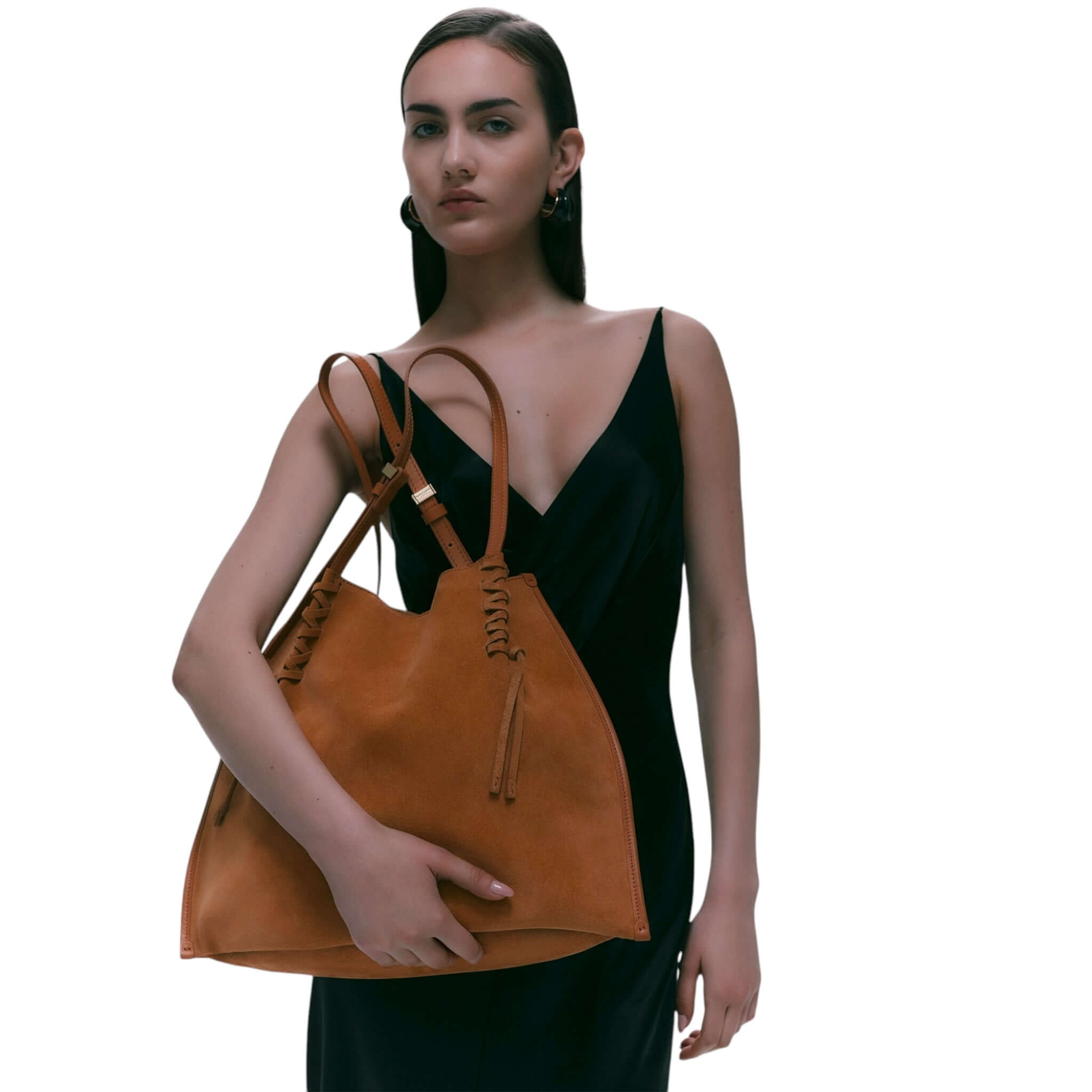 Model holding Dory handbag in soft suede, featuring a simple yet trendy design and unique twin strap details.